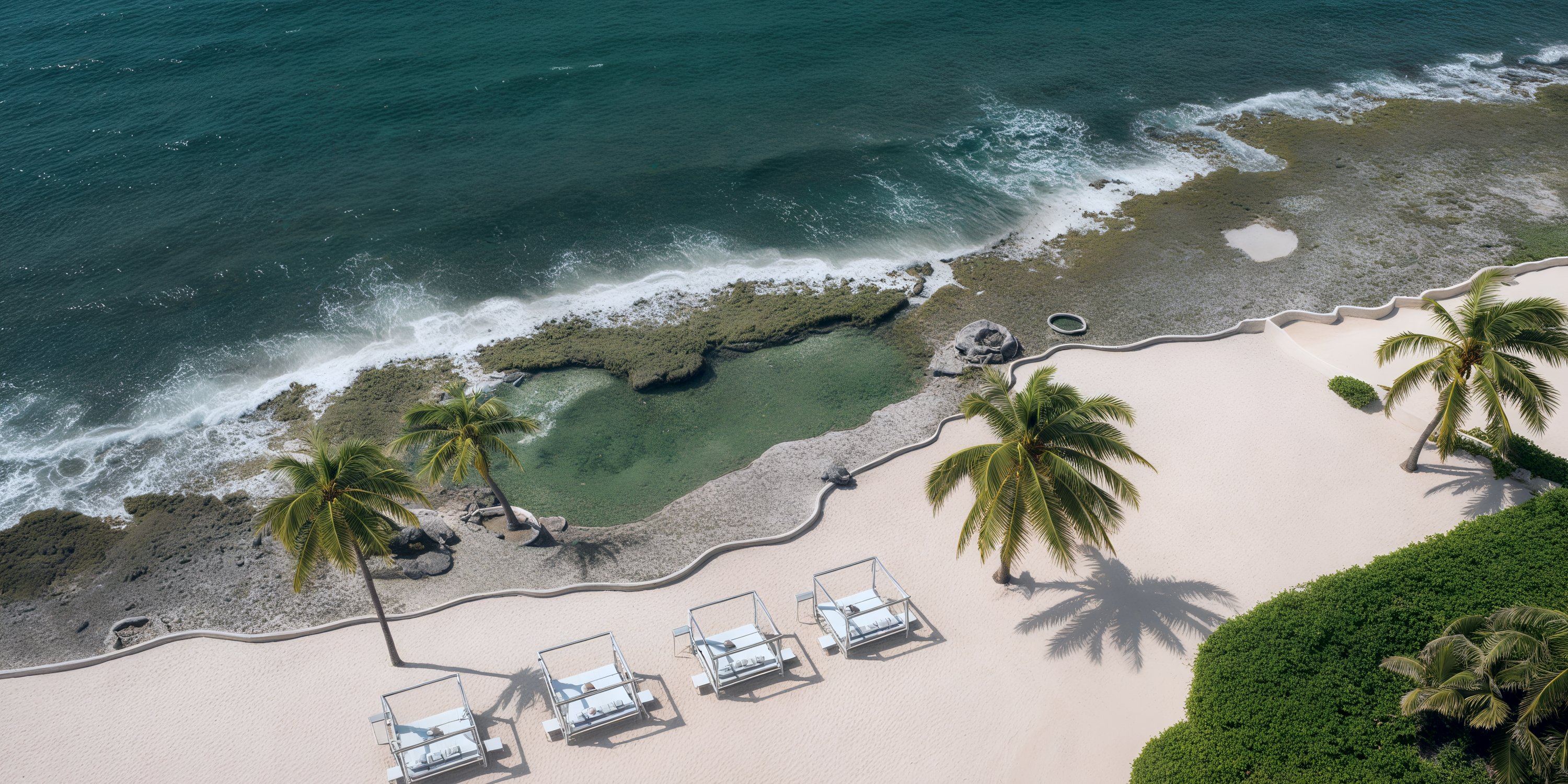 Four cabanas on white sand at a destination wedding resort, overlooking the ocean and rocky shore.