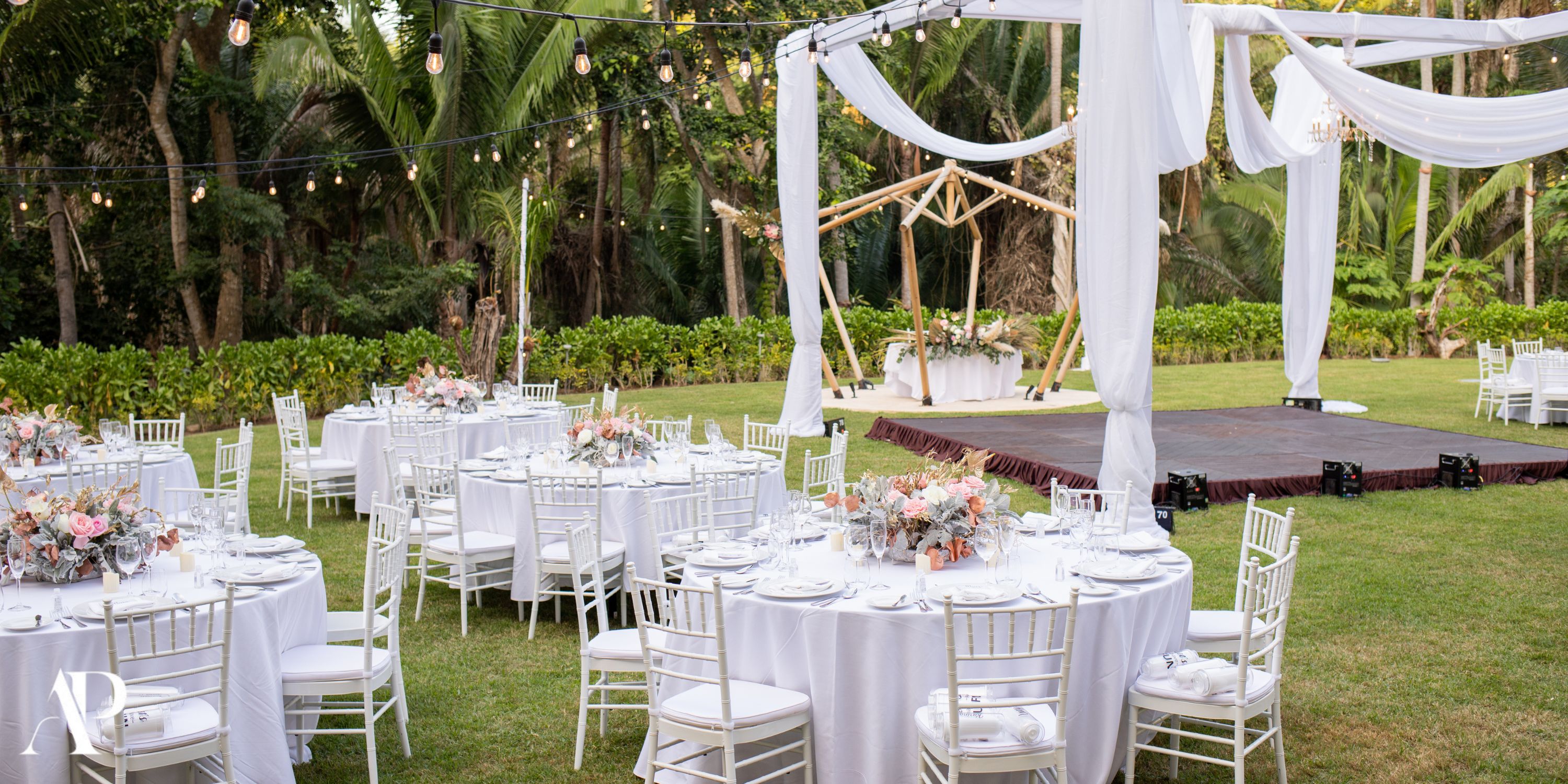Elegant destination wedding setup at Dreams Bahia Mita with round tables, white chairs, and a stylish stage.