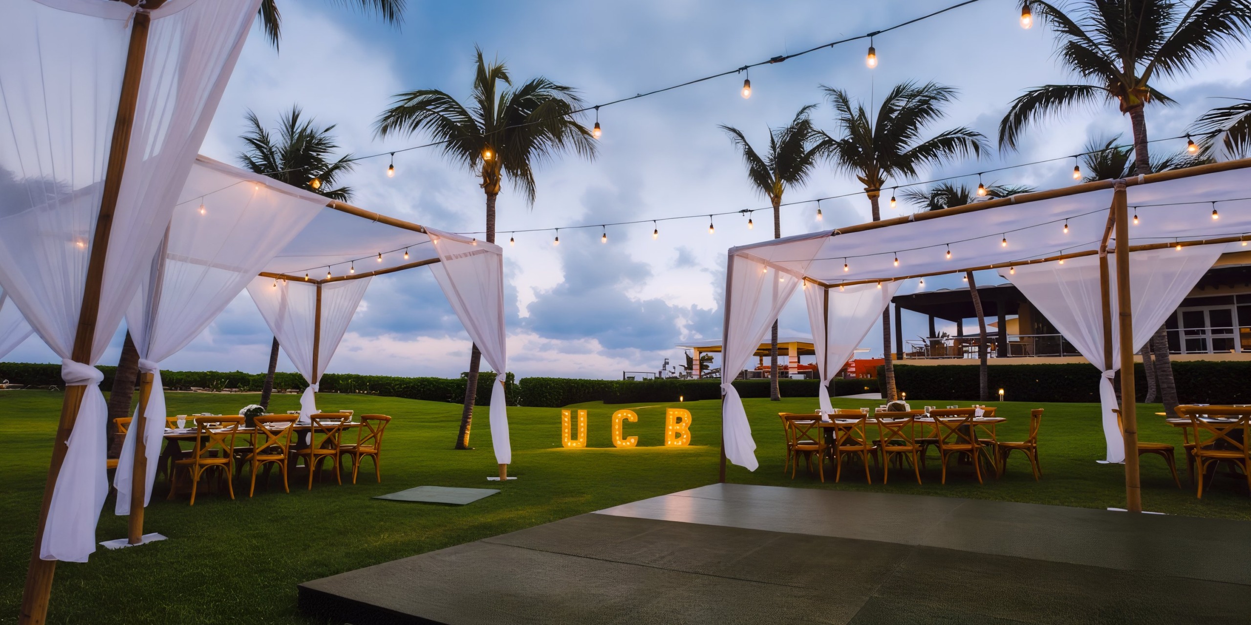 The destination wedding setup at Dreams Jade Riviera Cancun featured elegantly draped tents, enchanting string lights, and illuminated "UCB" letters.