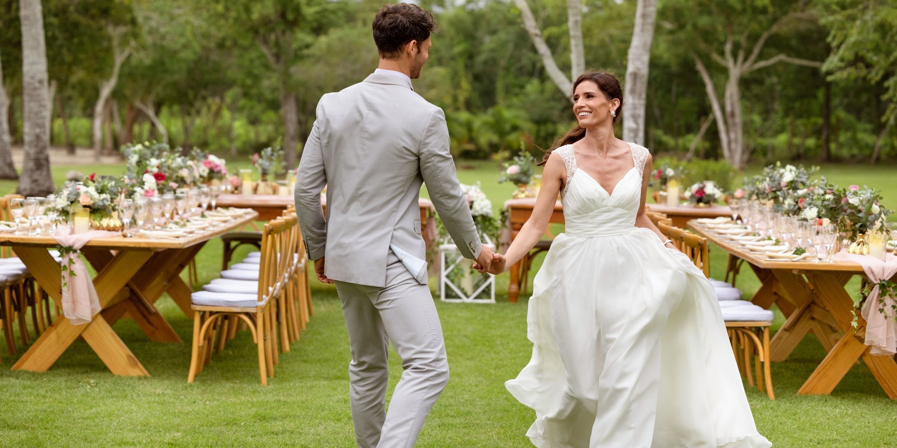 Bride and groom walk hand in hand outdoors at a Dreams La Romana destination wedding reception.