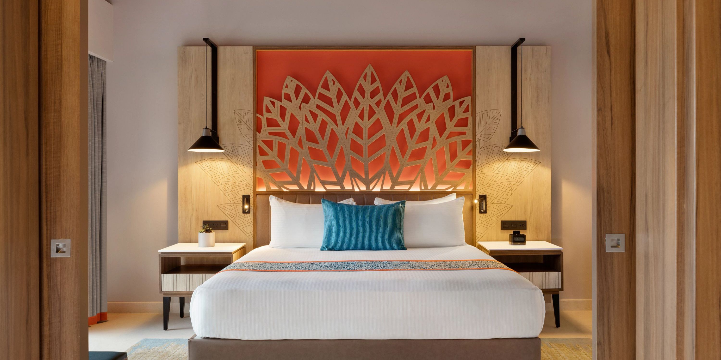 Modern Hilton La Romana room, perfect for a destination wedding stay, featuring a king bed with an eye-catching orange leaf headboard and elegant bedside lamps.