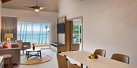 Experience a modern living and dining area at Hilton La Romana, perfect for your destination wedding, featuring an ocean view, a private balcony, and a welcoming fruit bowl.