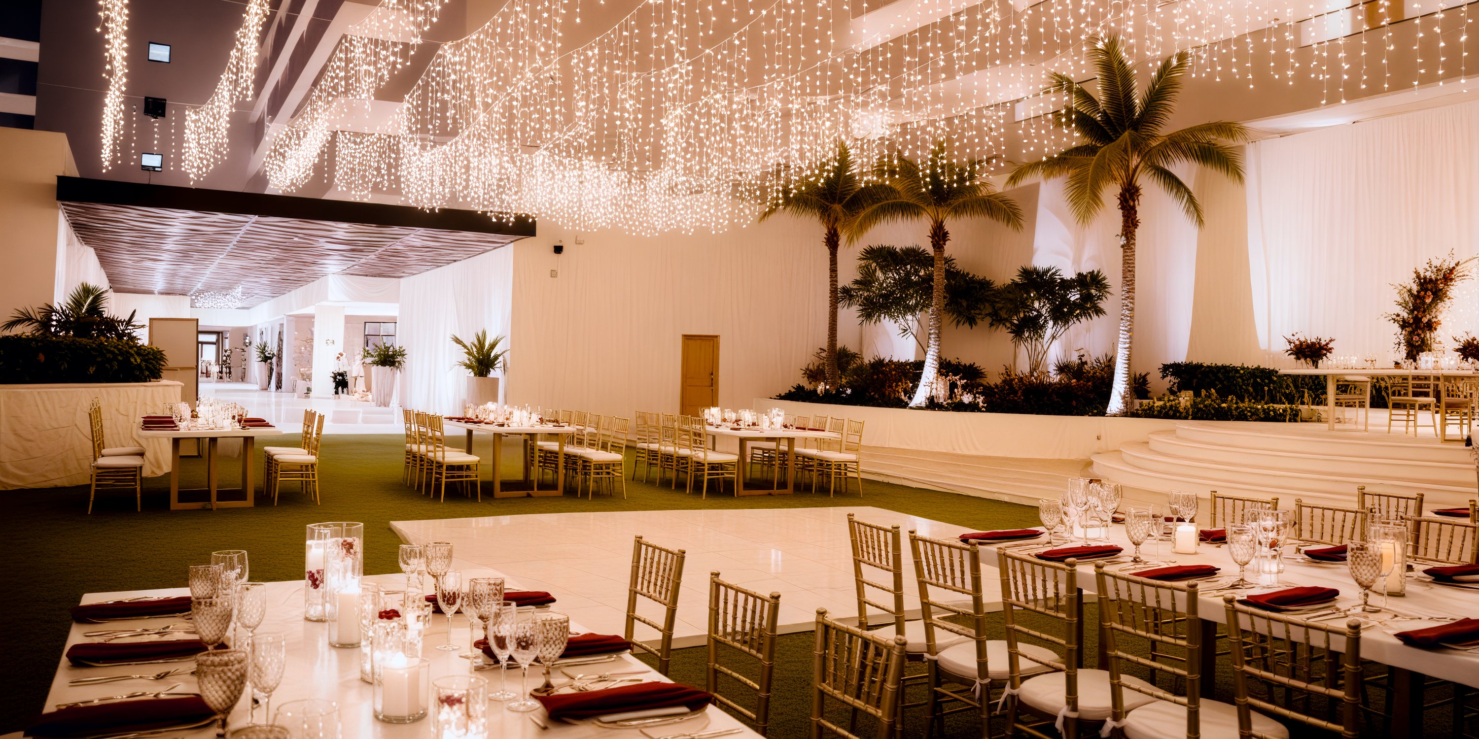 Dreams Natura offers an elegant indoor wedding venue adorned with draped lights, lush palm trees, and beautifully decorated dining tables—perfect for a romantic destination wedding.
