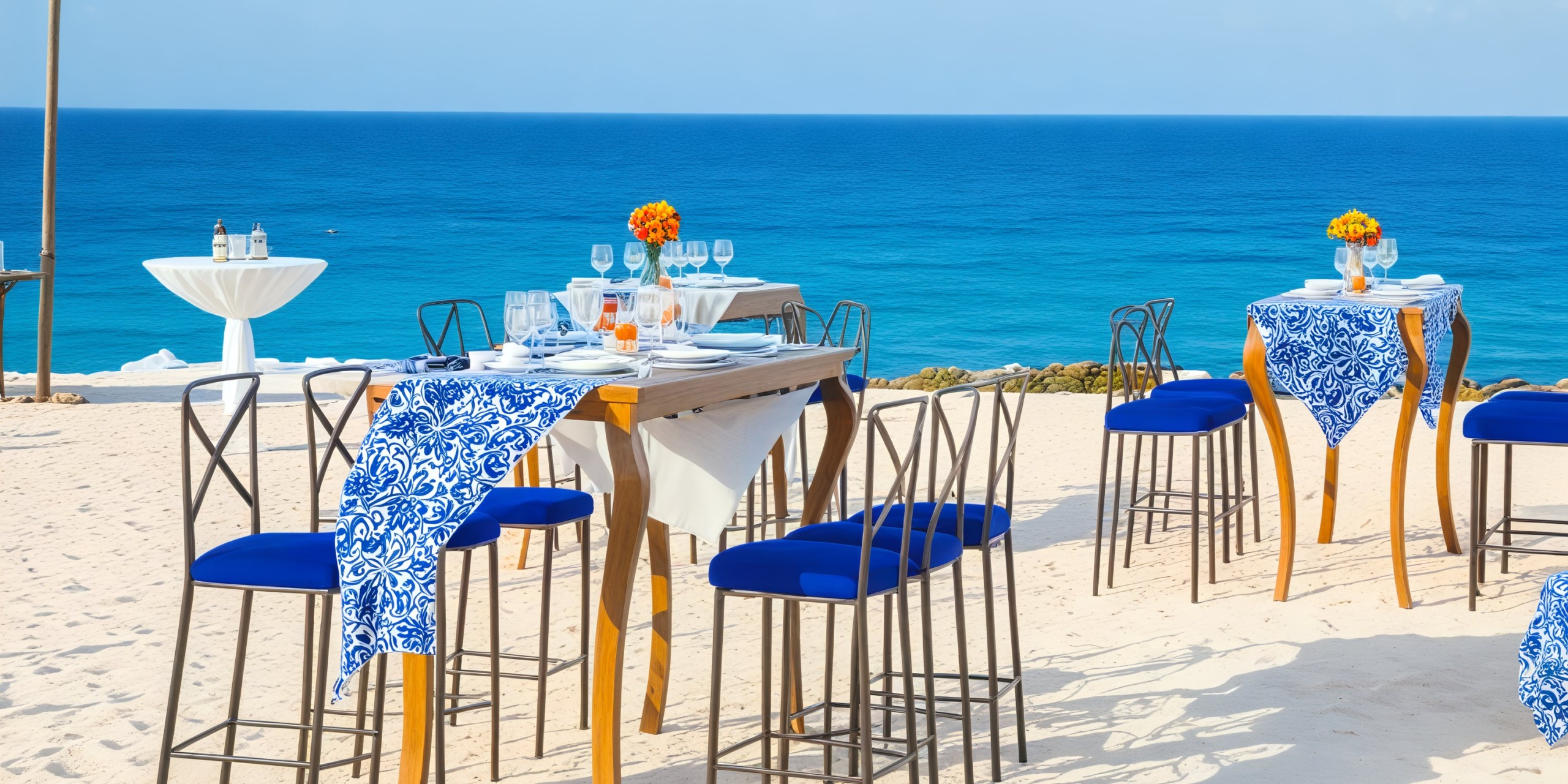 Blue decor tables are elegantly arranged on the sandy beach at Secrets Playa Mujeres, offering a stunning sea view, perfect for a destination wedding.