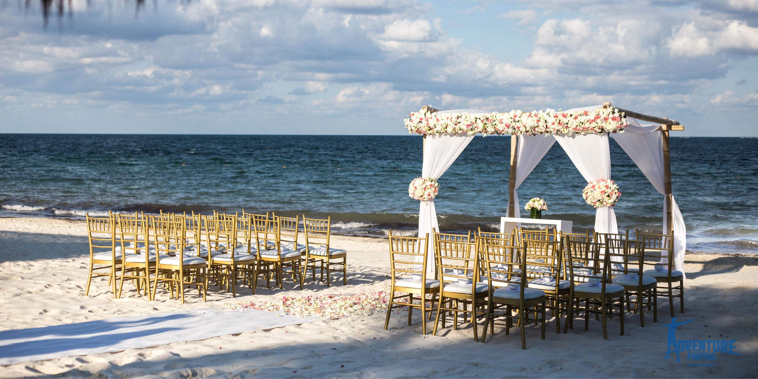 Dreams Sapphire destination wedding setup with rows of chairs and floral arch by the ocean beach.