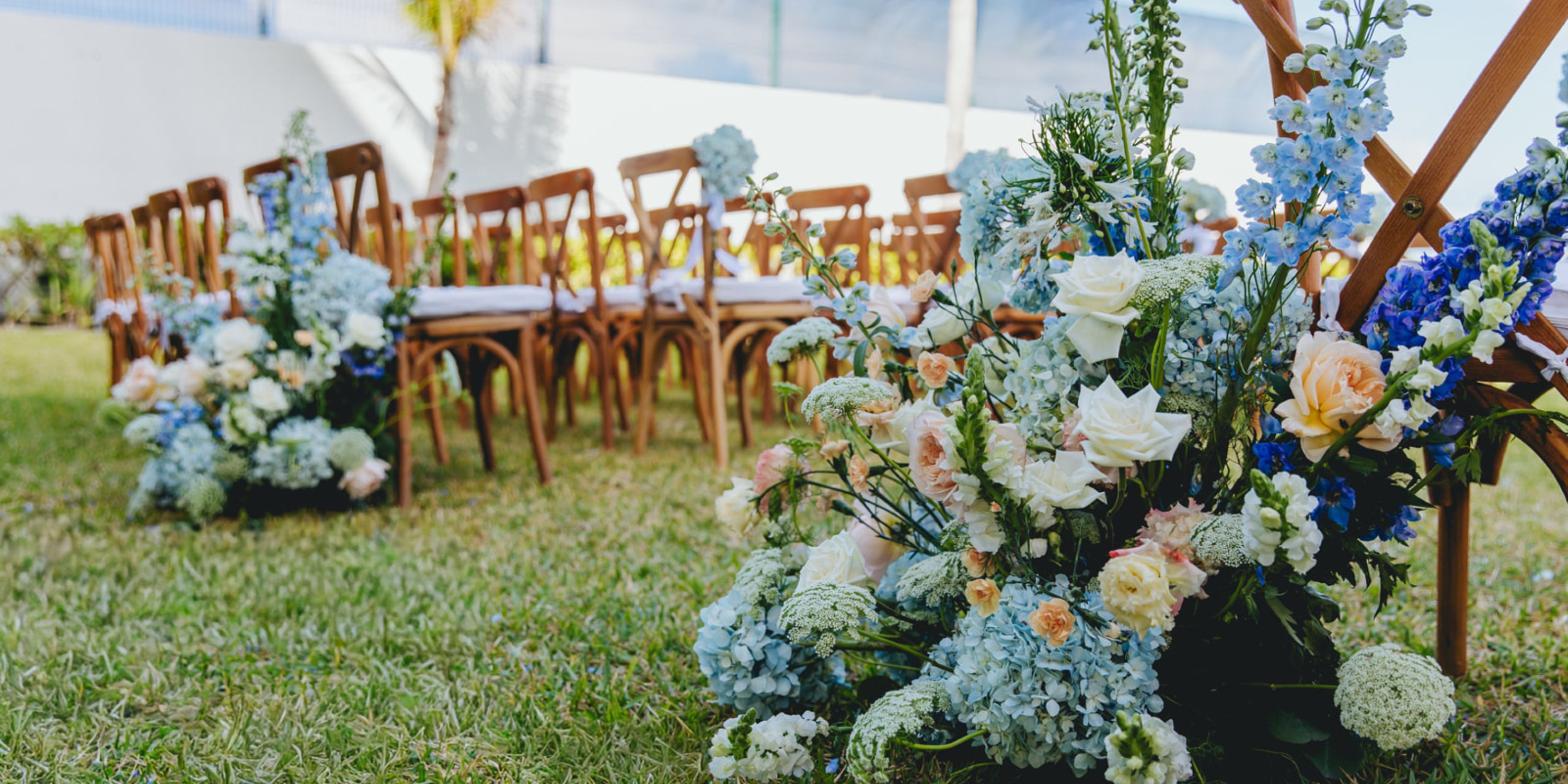 Dreams Sapphire destination wedding setup with wooden chairs and pastel flowers for an outdoor ceremony.
