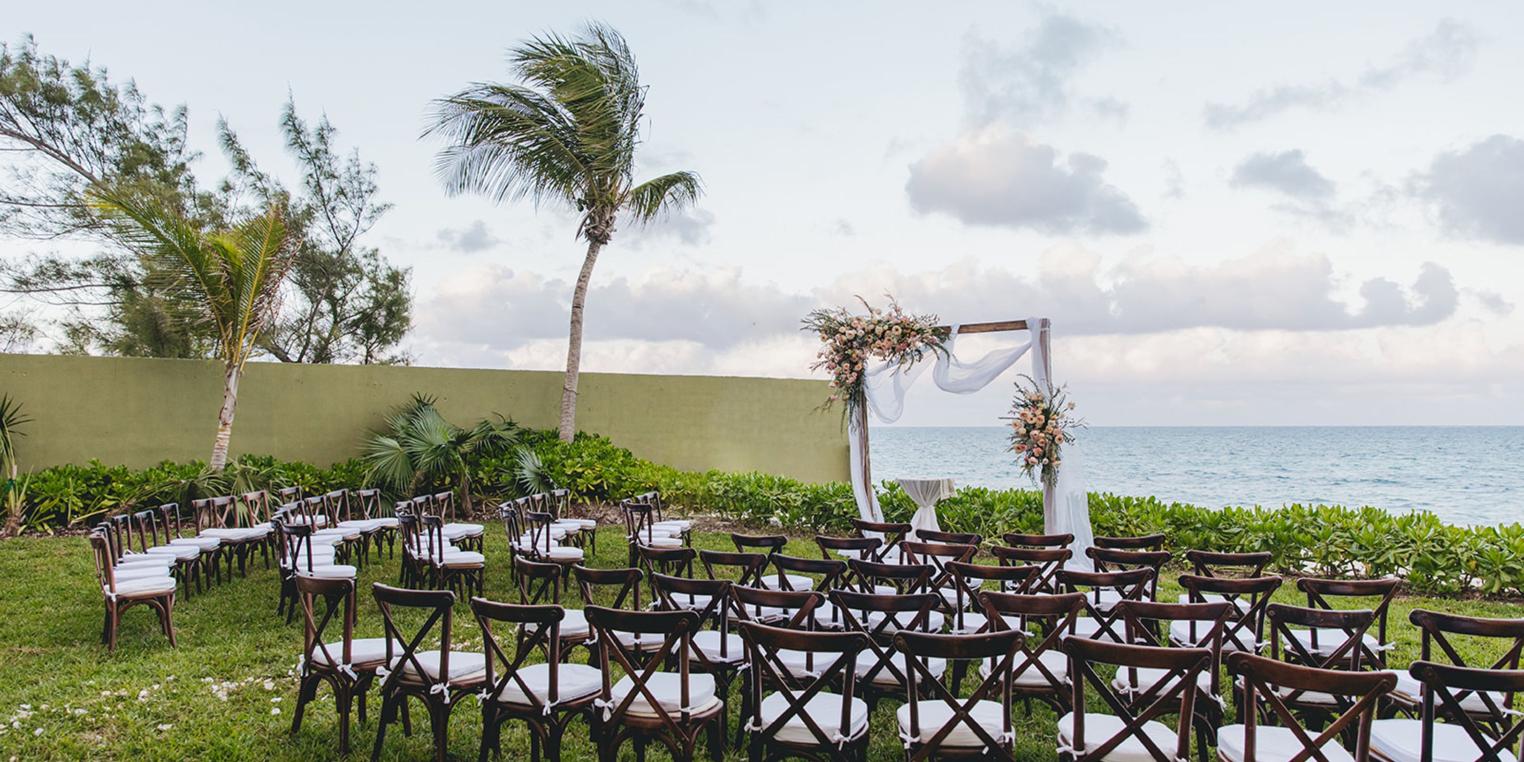 Destination wedding setup at Dreams Sapphire with ocean view, lined chairs, and a floral wedding arch.