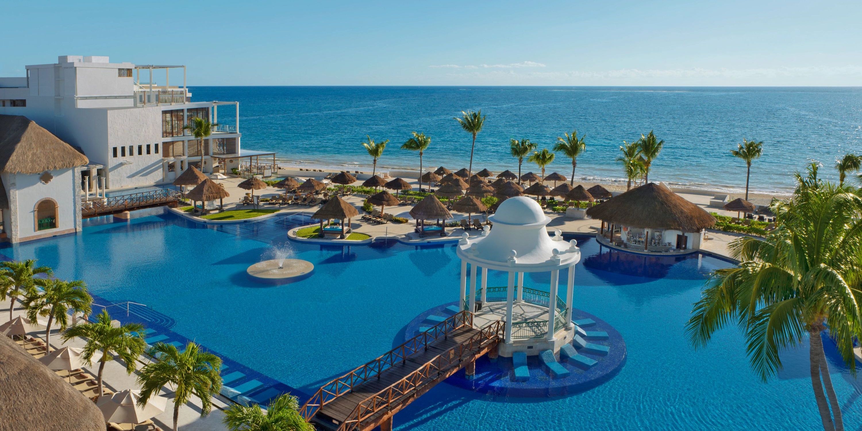 Dreams Sapphire: Ideal destination wedding spot with large pool, white gazebo, palms & ocean backdrop.