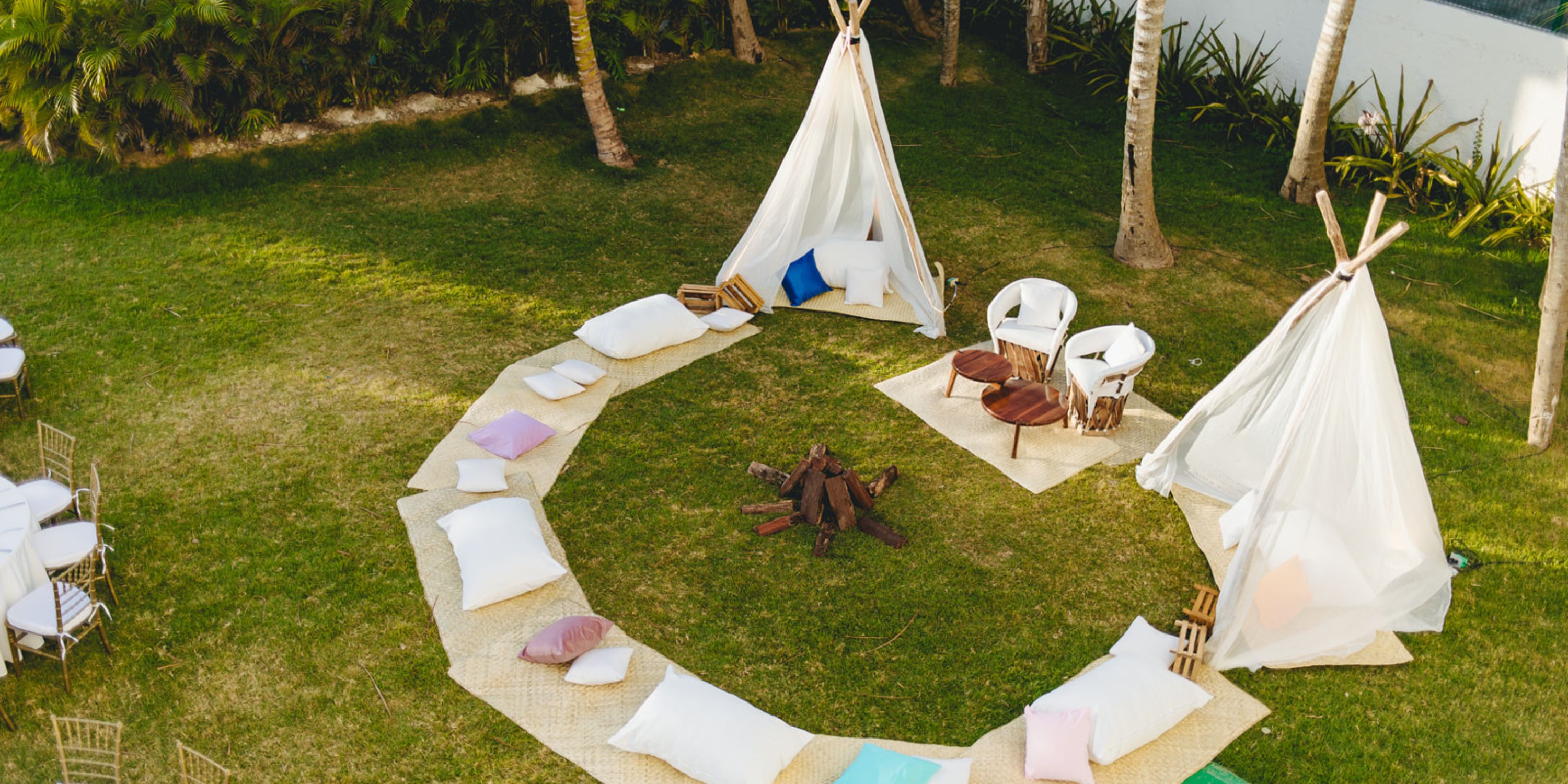 Dreams Sapphire: Outdoor wedding area with circle of cushions, two teepees, and central firewood.