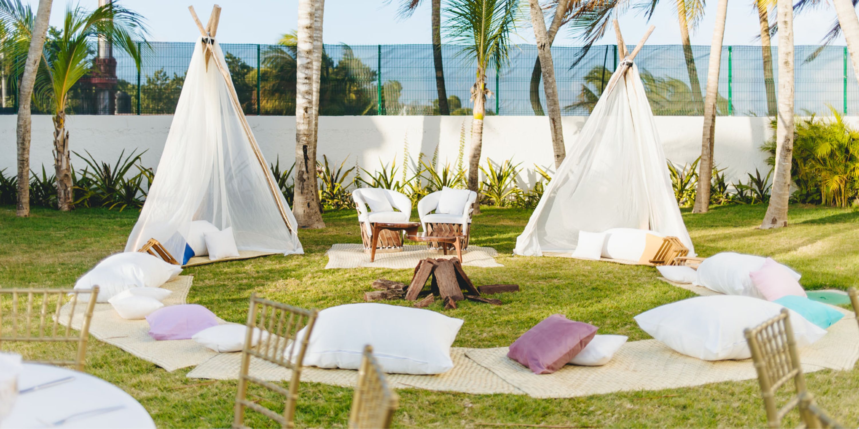 Dreams Sapphire: Outdoor seating with pillows, chairs, and two white tents by a firepit for a destination wedding.