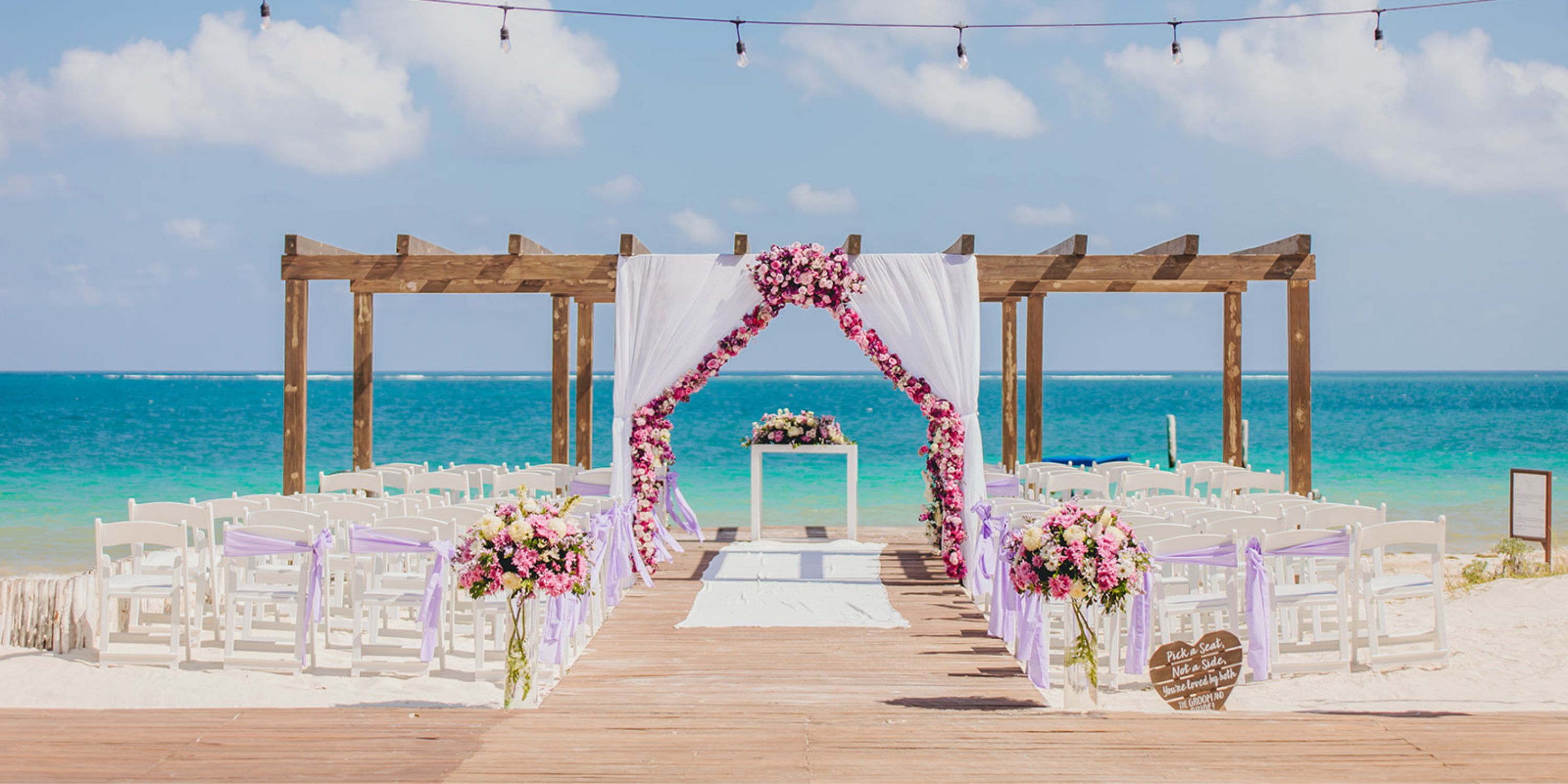 Destination wedding setup at Dreams Sapphire: white chairs, floral decor, and a stunning ocean backdrop.