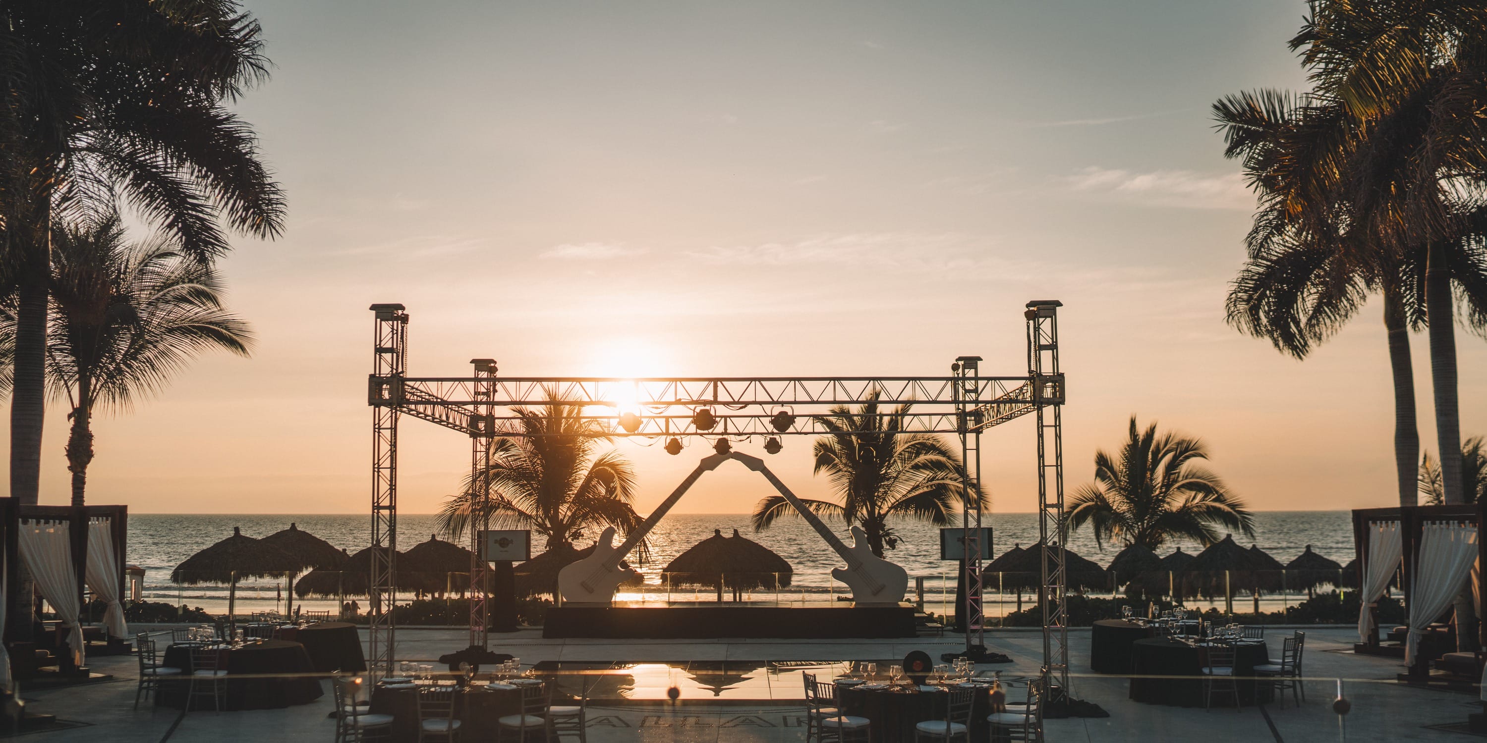 A guitar-shaped Hard Rock Vallarta wedding stage on a beachfront terrace at sunset.