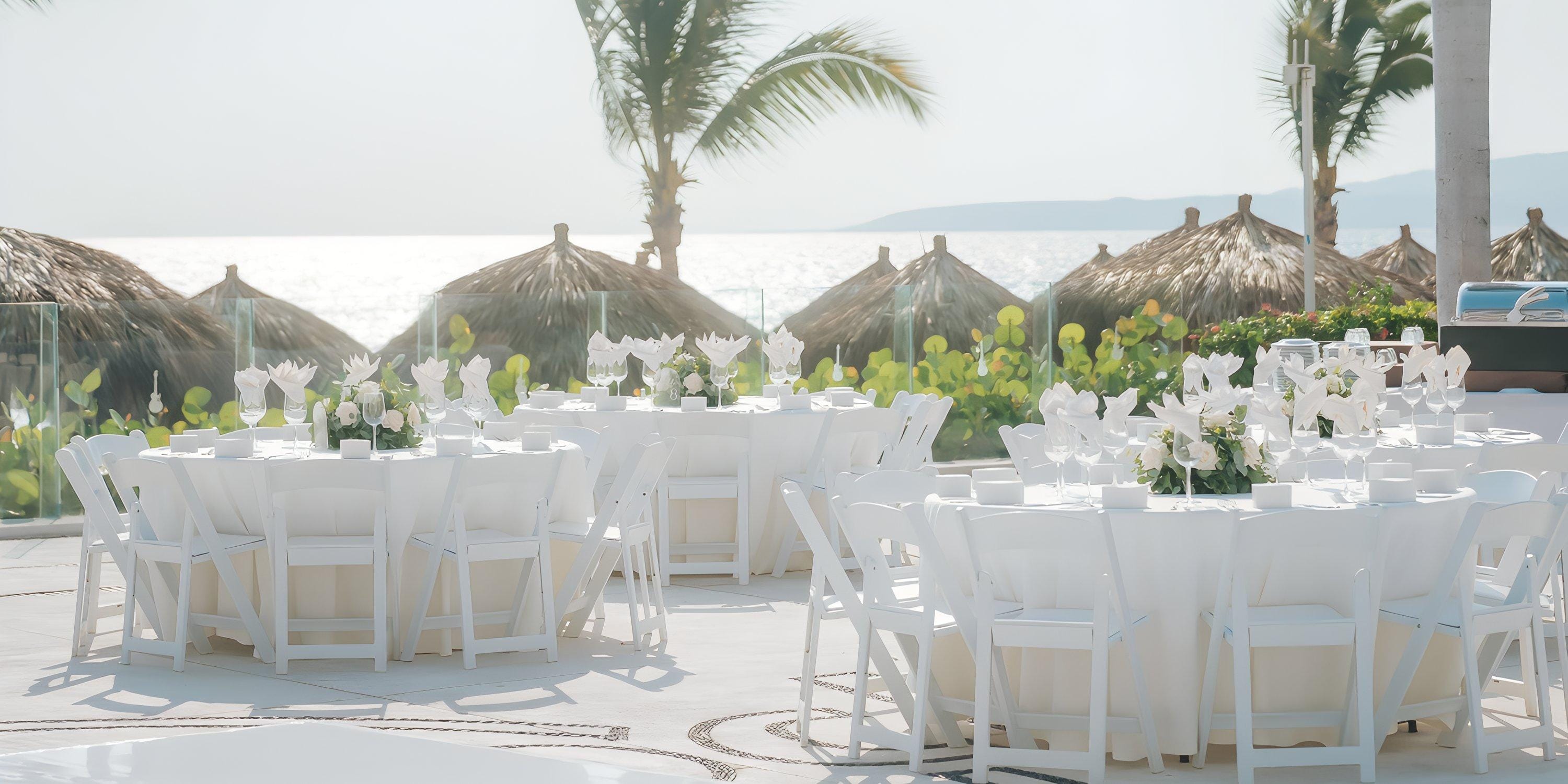 Outdoor tables arranged for a destination wedding at Hard Rock Vallarta, with palm trees and thatched huts.