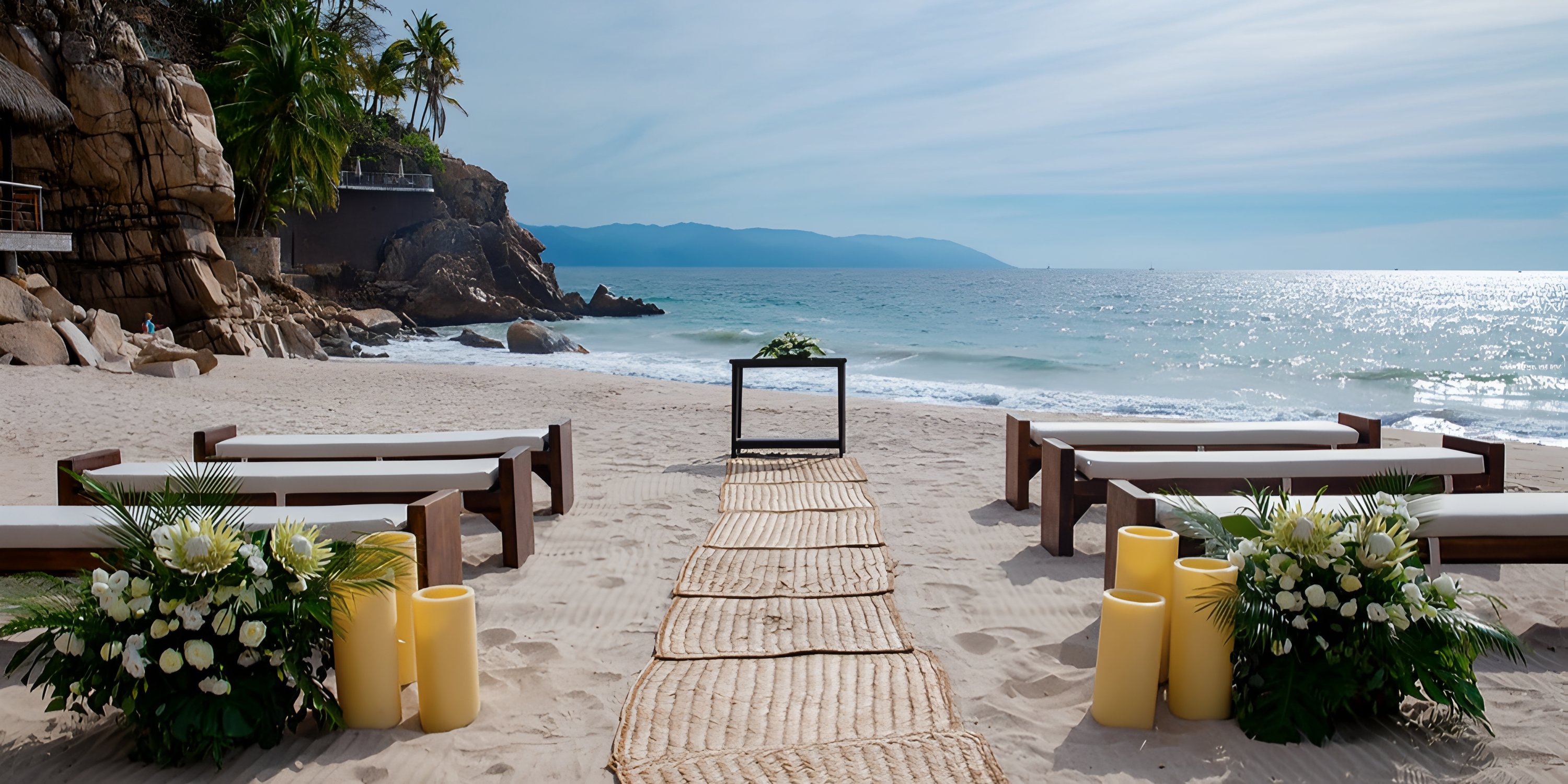 Destination wedding at Hyatt Ziva Puerto Vallarta with benches, flowers, candles, and an oceanfront altar.
