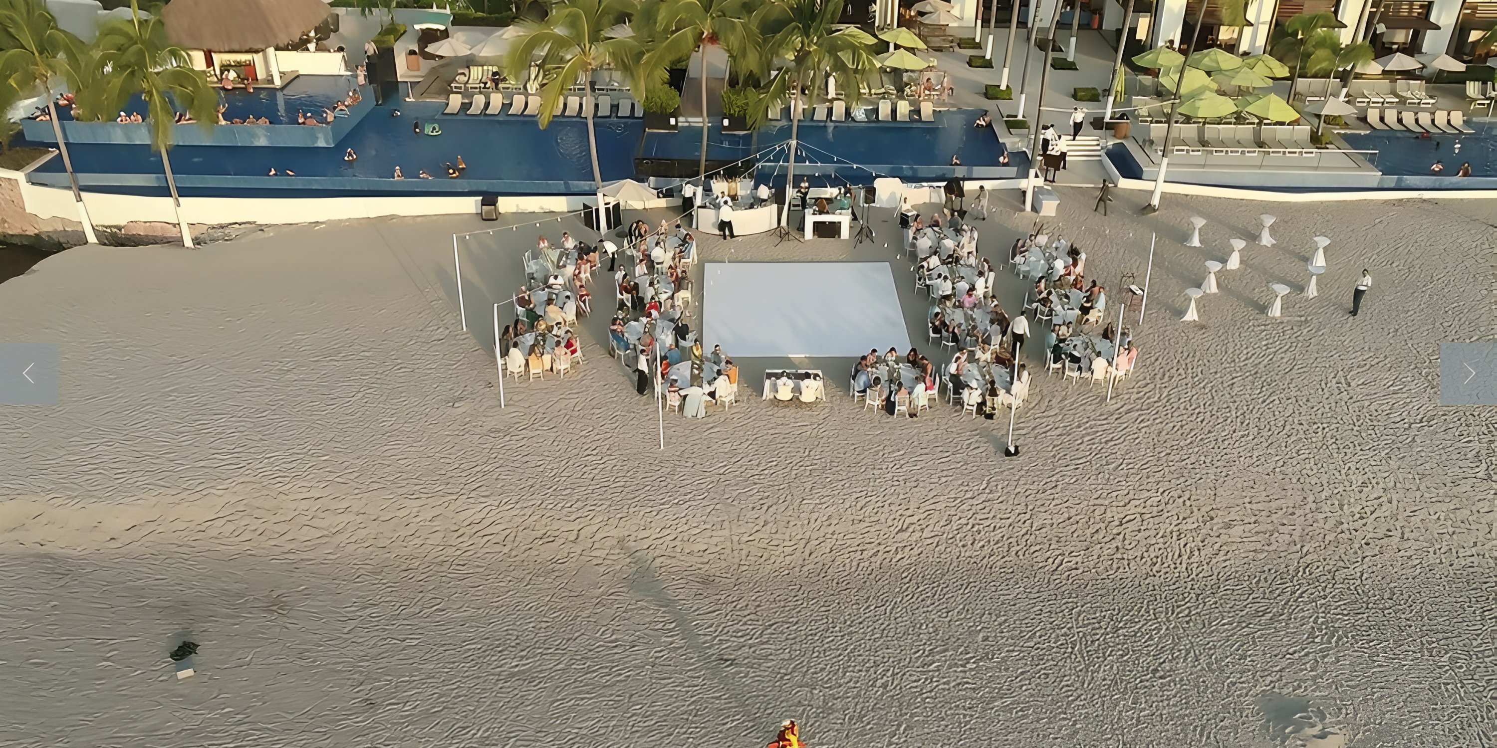 Aerial view of a destination wedding setup with tables and guests gathered by the pool at Hyatt Ziva.