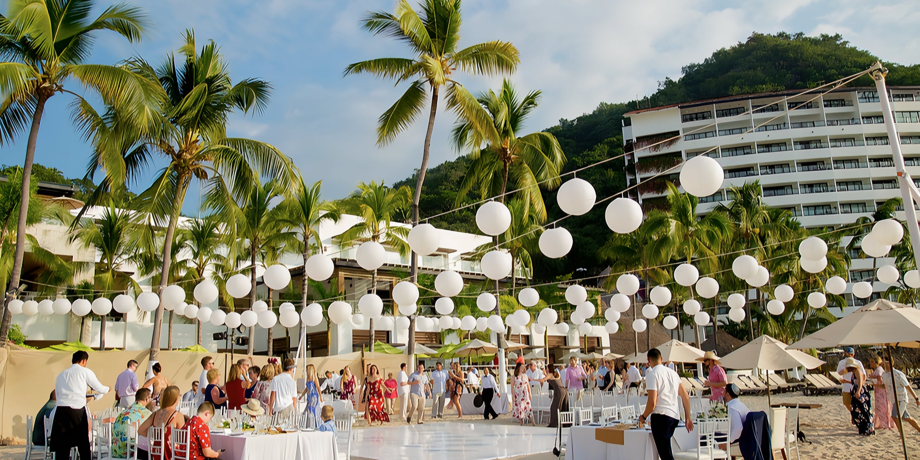 Guests arrive for a destination wedding at Hyatt Ziva Puerto Vallarta, with tables, string lights, and palm trees.