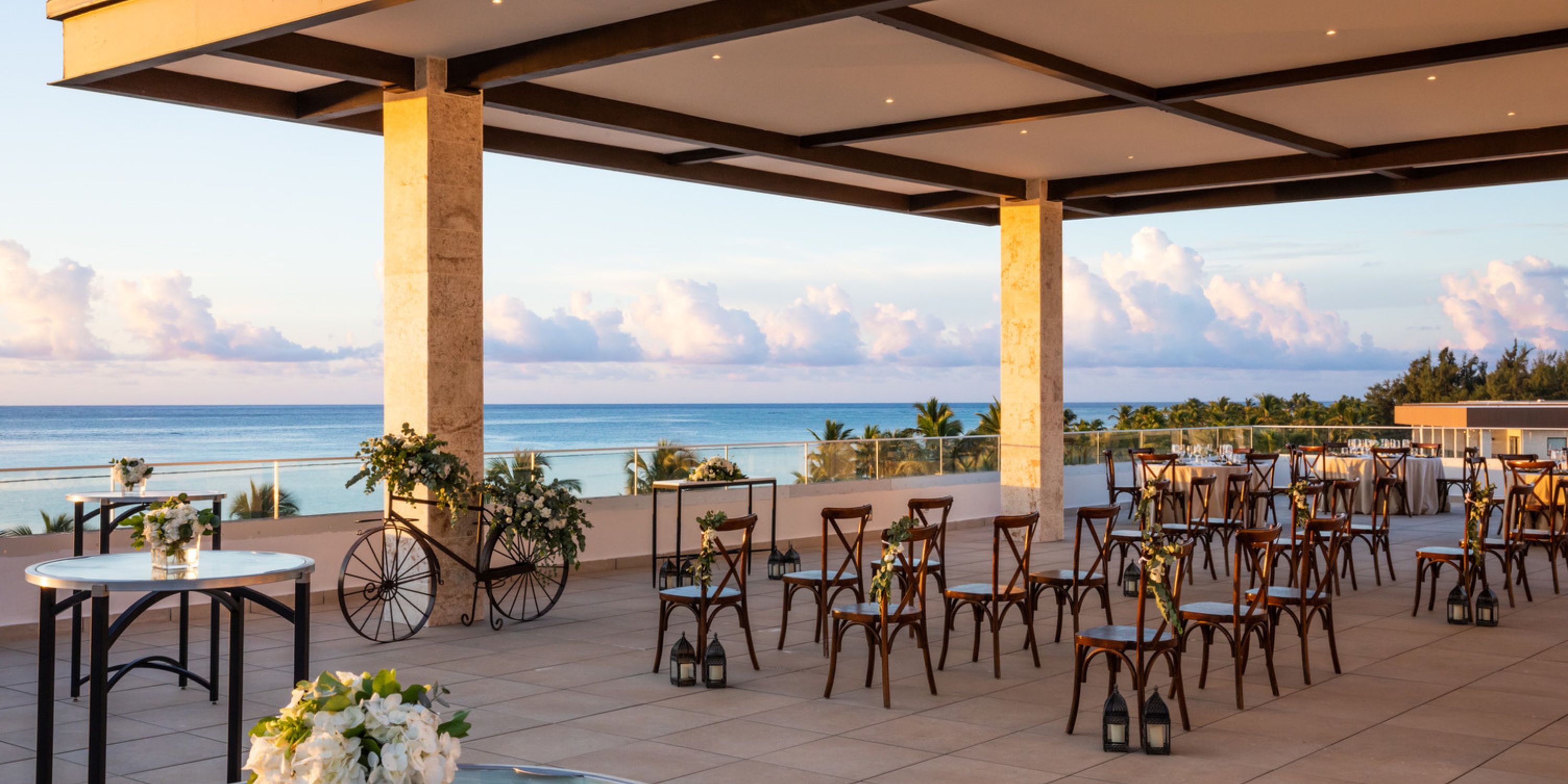 The terrace at Hyatt Ziva Cap Cana provides a picturesque setting for a destination wedding, offering chairs and tables where guests can enjoy breathtaking sunset ocean views.