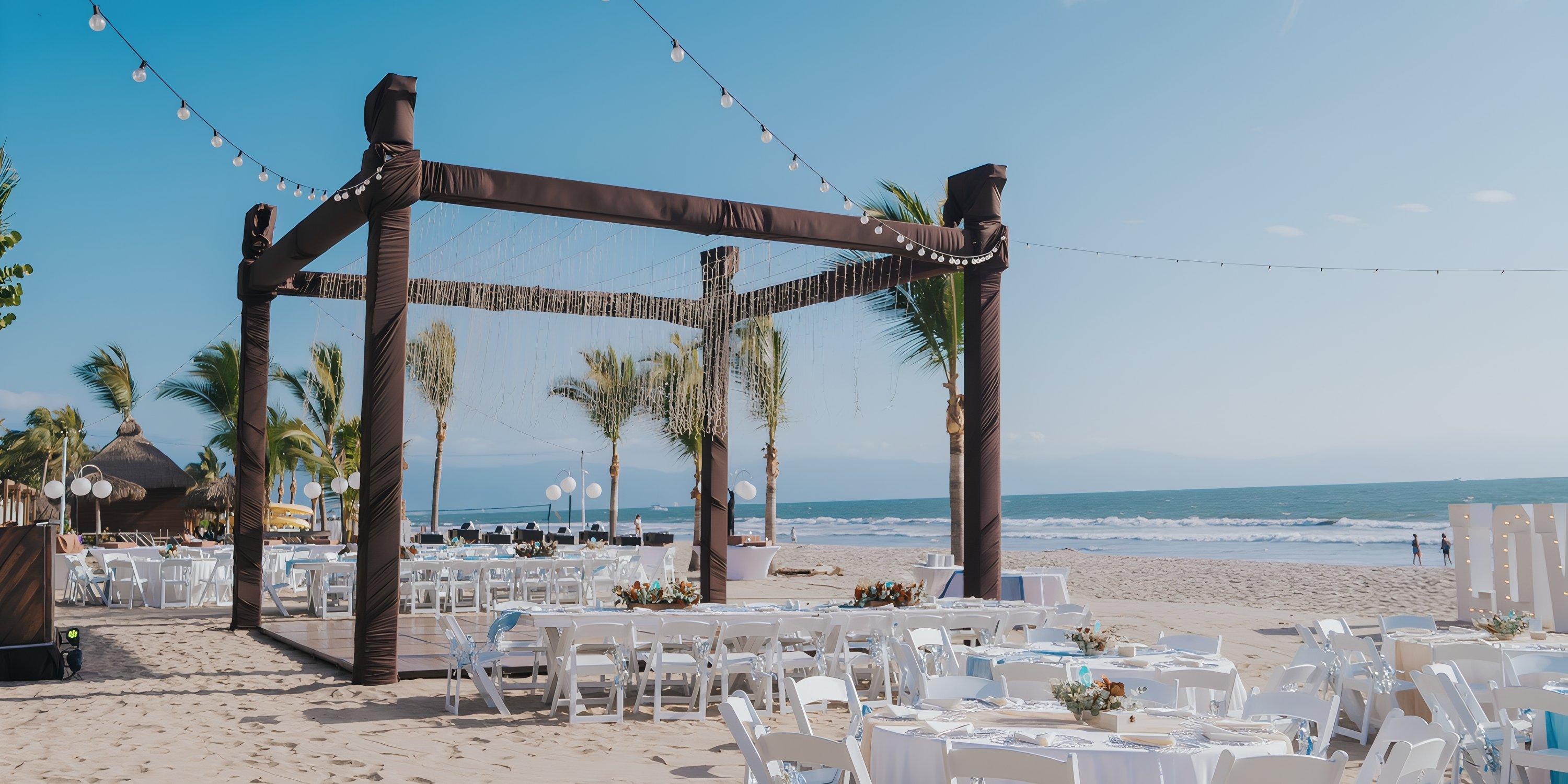 Destination wedding setup at Hard Rock Vallarta: white tables and chairs arranged on a beach by the ocean.