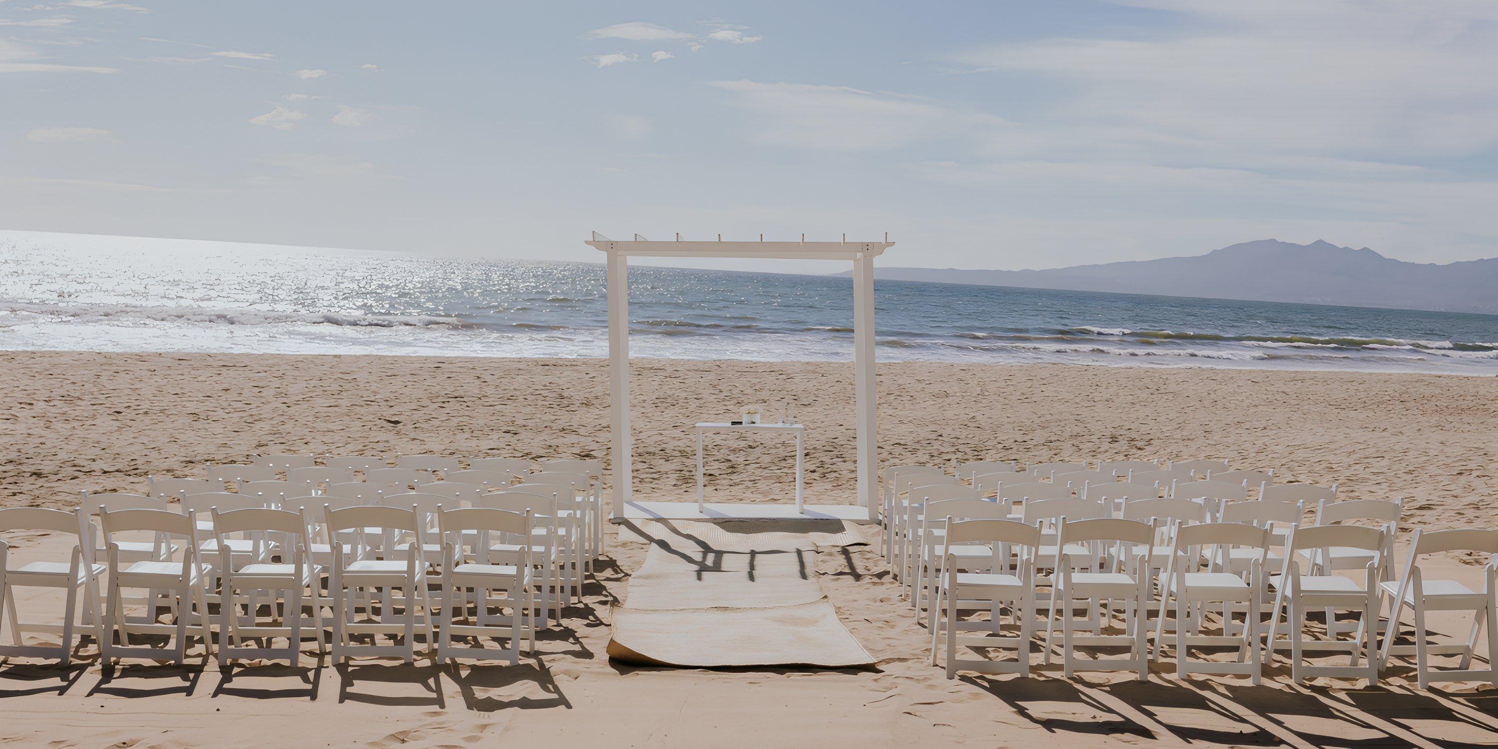 White chairs and an arch arranged for a destination wedding ceremony on the beach at Hard Rock Vallarta.