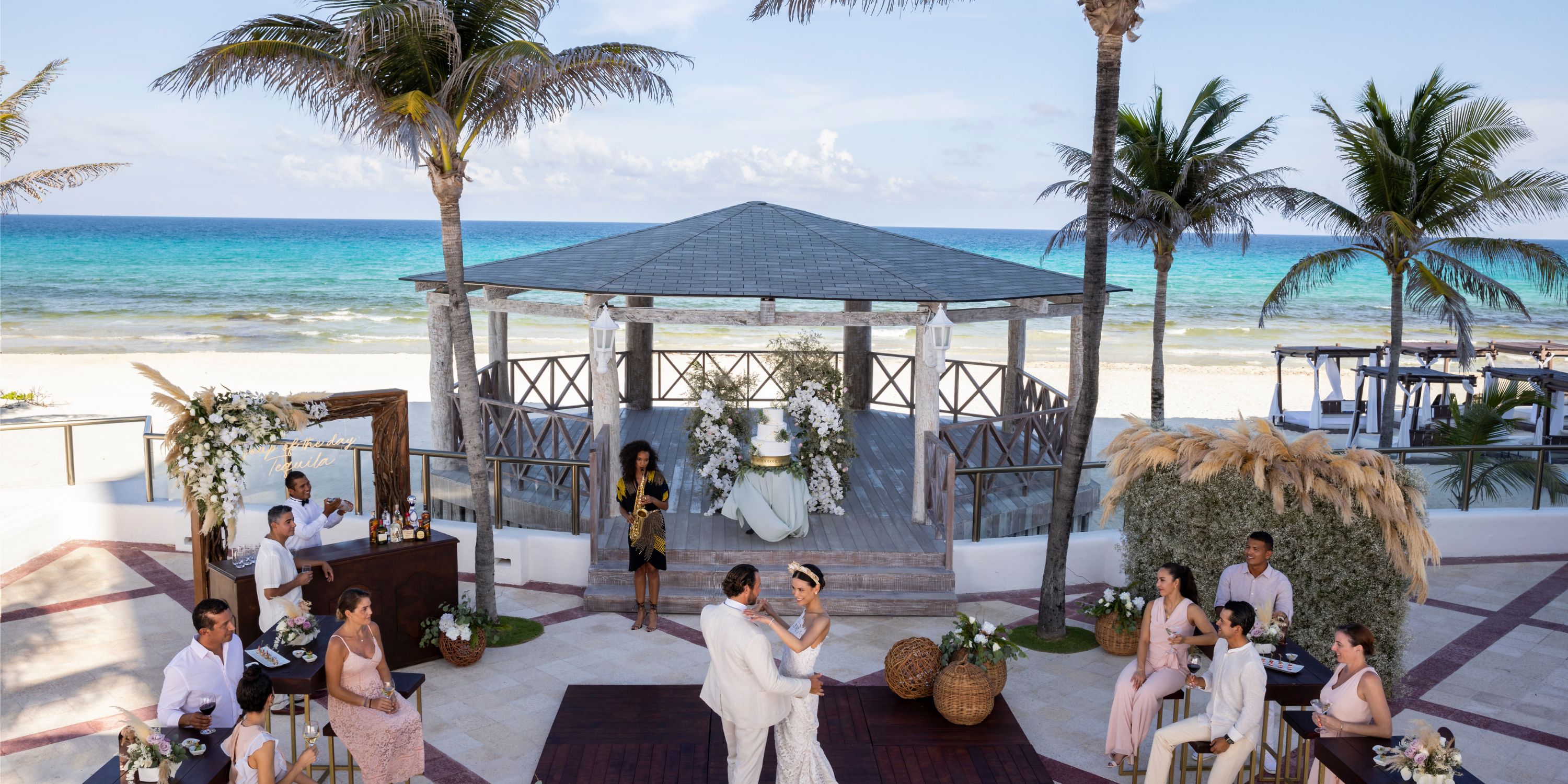 A couple shares a dance at their destination wedding on the beach at Hyatt Zilara Cancun, guests watching nearby.
