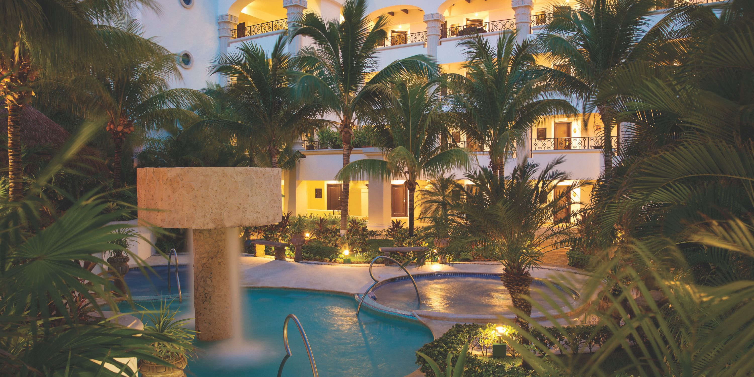 Hyatt Zilara Cancun&rsquo;s pool, ideal for a destination wedding, glows at dusk amid palms and balconies.