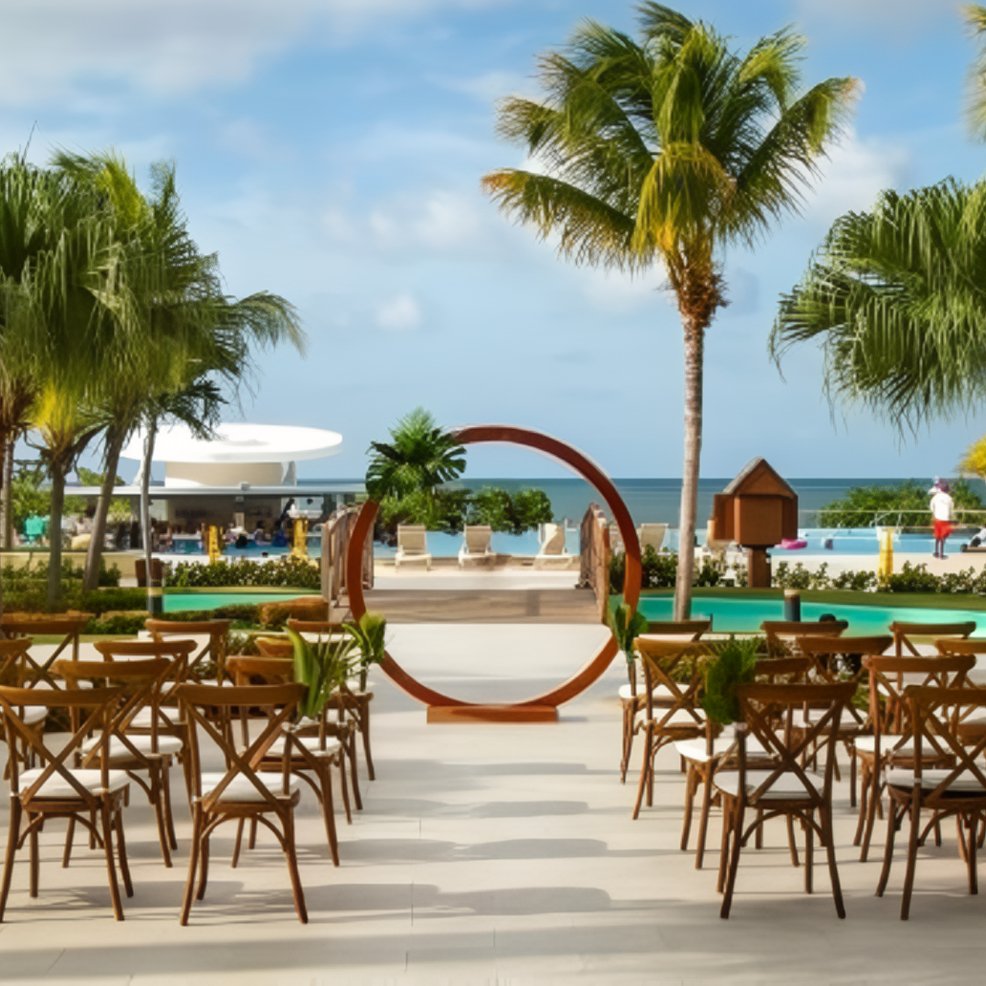 Rows of wooden chairs face a circular arch at a beachside destination wedding venue outdoors.