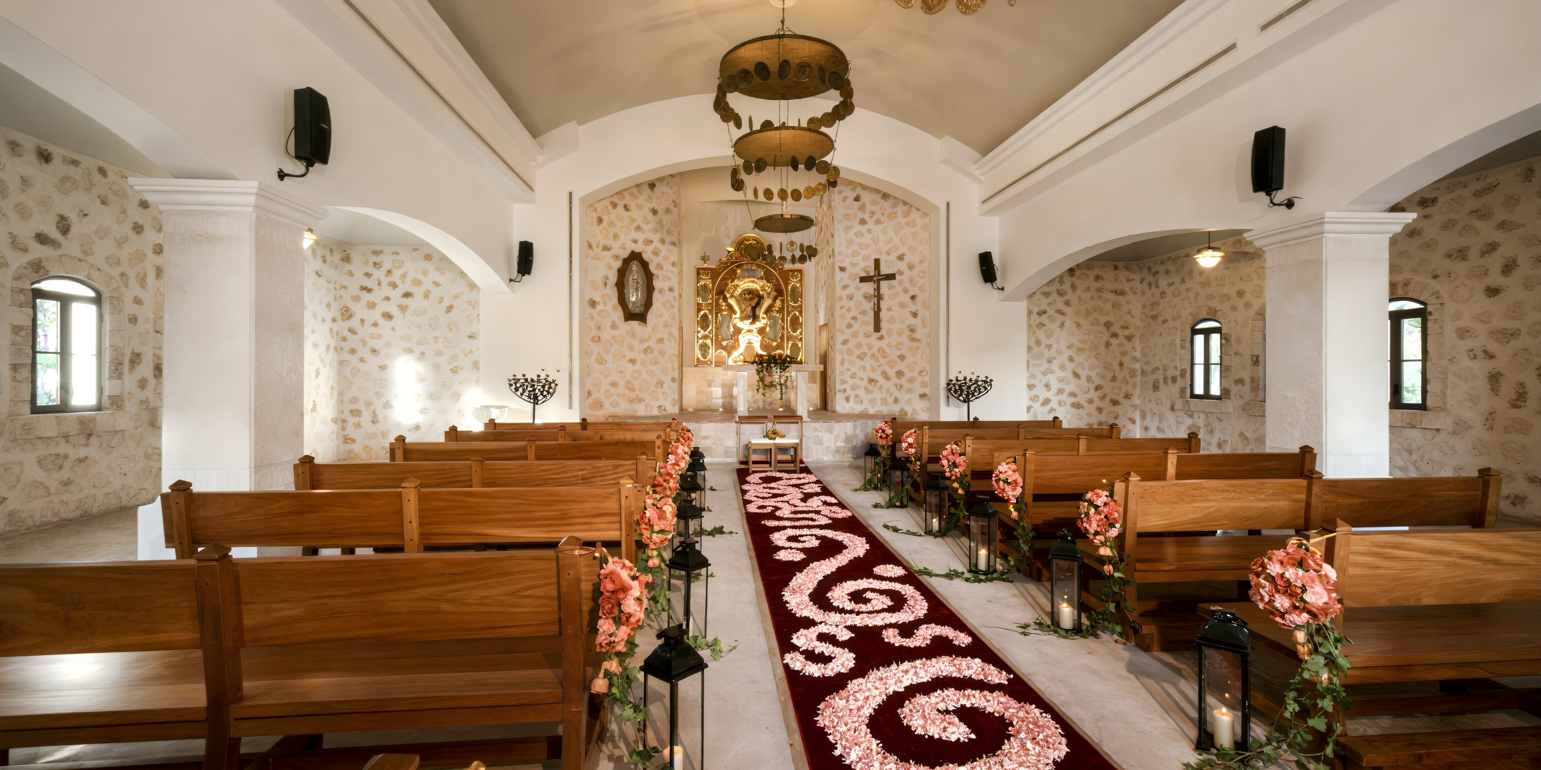 Iberostar Selection Paraiso Lindo: wedding chapel with wooden pews, floral aisle, and gold altar icon.