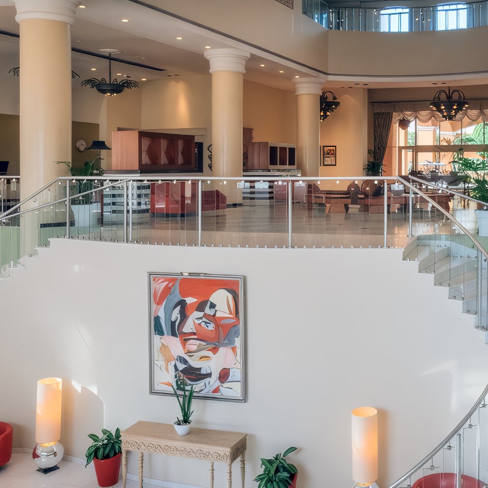 Elegant hotel lobby perfect for a destination wedding, featuring staircase, abstract art, pillars, and seating.