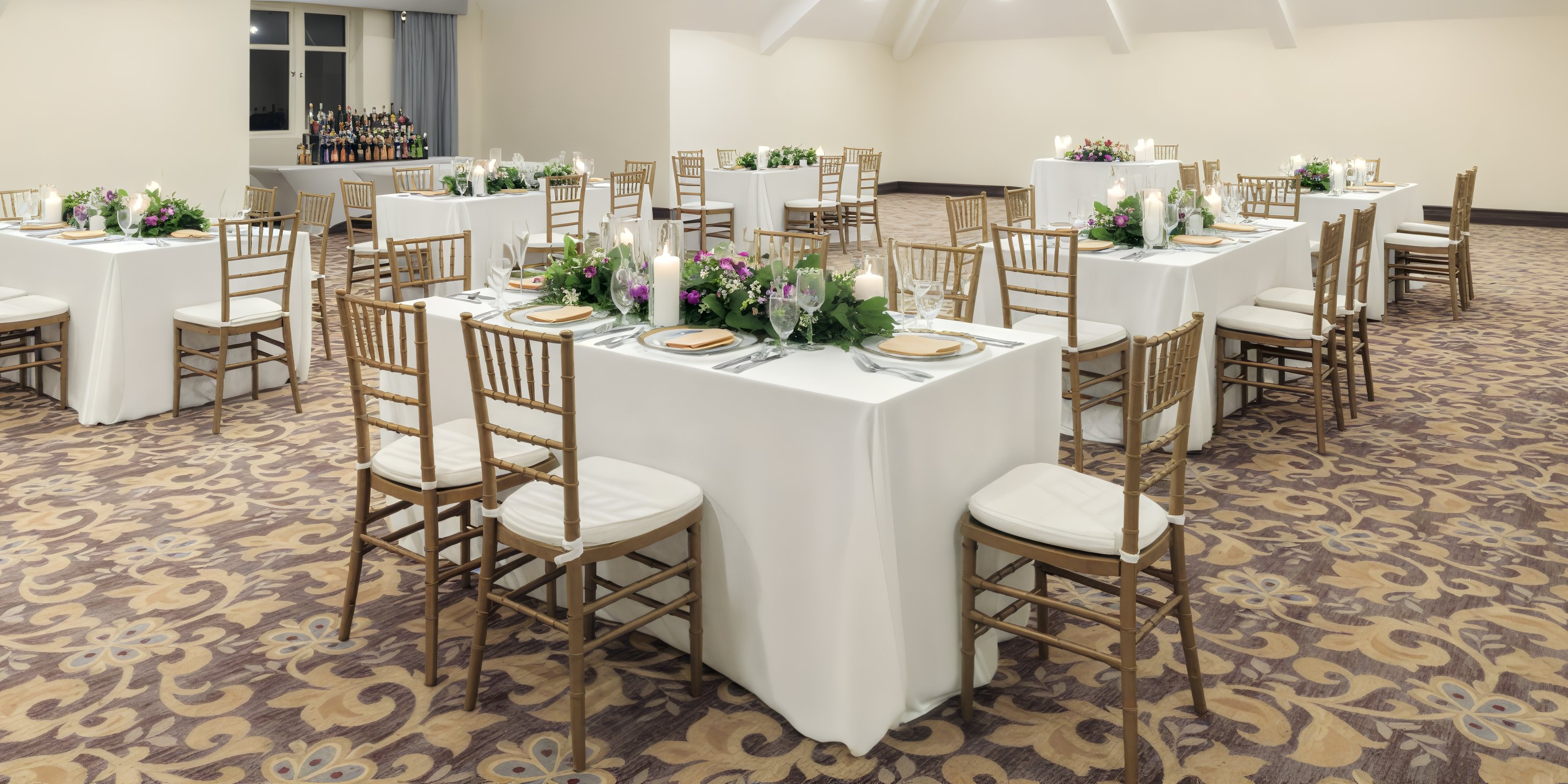 Rectangular tables with white linens and floral centerpieces set for a destination wedding at Jewel Grande.