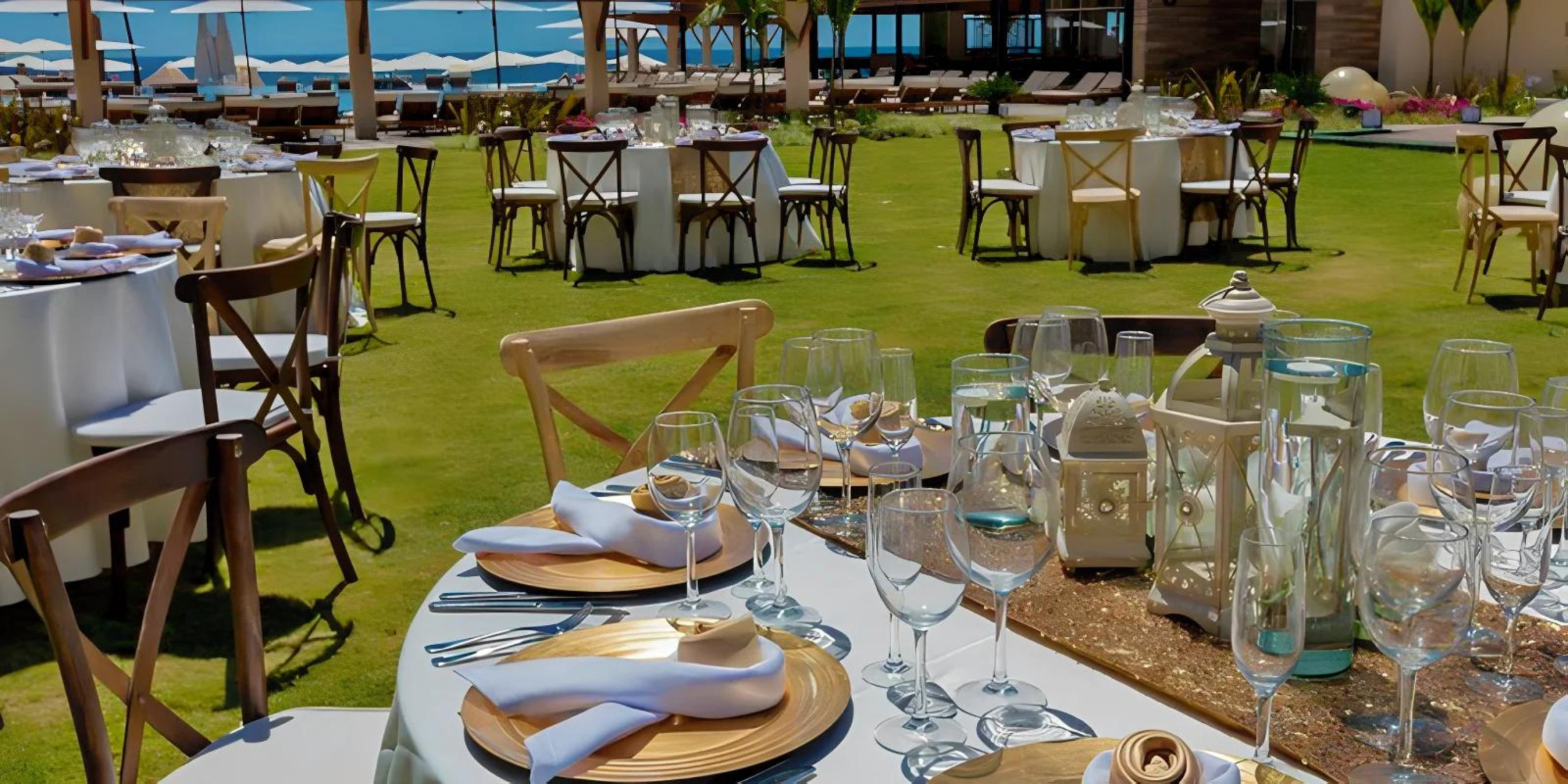 Outdoor dining setup at a luxury resort for destination weddings, with elegantly set tables, ocean view, and white umbrellas.