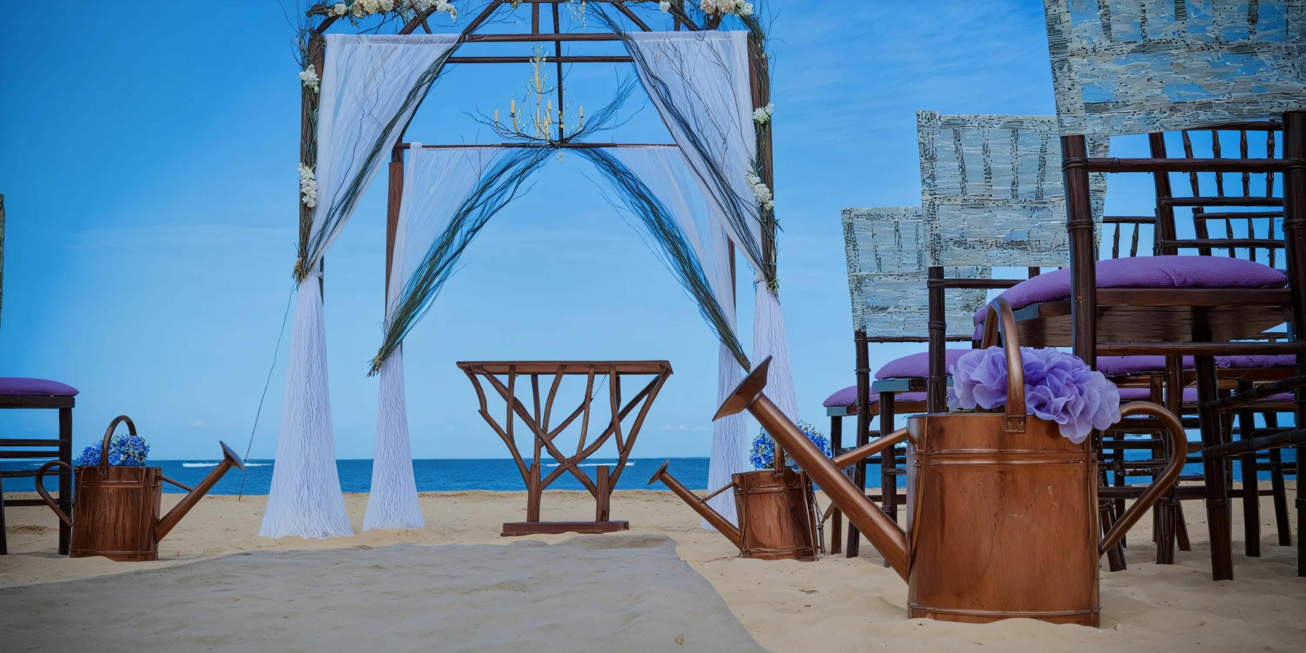 A Dreams Onyx beach wedding setup showcasing a decorated arch adorned with white drapes, complemented by wooden chairs with luxurious purple cushions and bronze watering cans brimming with vibrant purple flowers. The breathtaking ocean serves as the perfect backdrop.