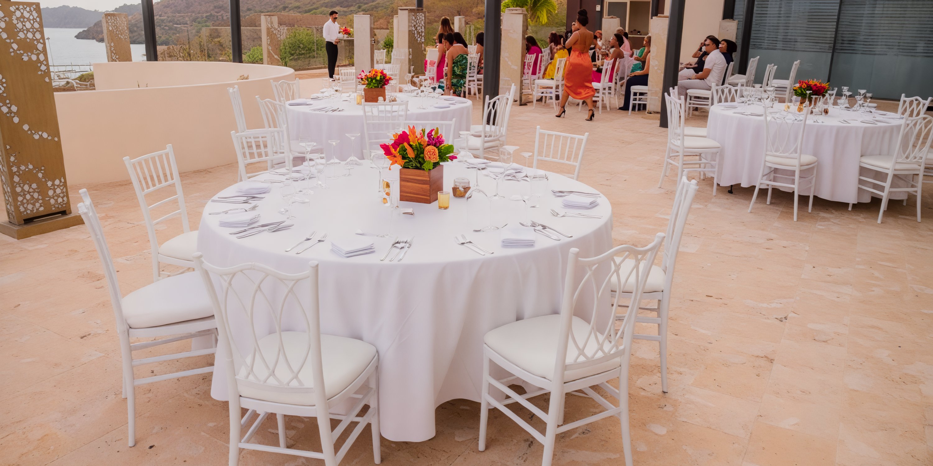 Guests gather at Planet Hollywood Costa Rica for a beautiful destination wedding, seated around round tables adorned with elegant white chairs.