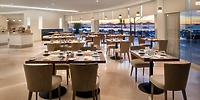 The dining experience at Elegant Playacar Palace is perfect for a destination wedding, with beautifully set tables in a spacious area and stunning ocean views through large windows.