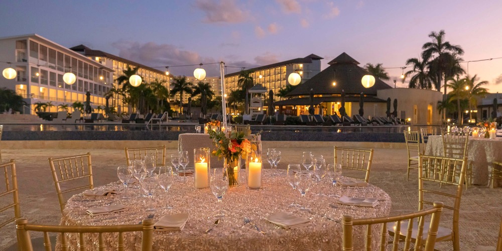 Round table with candles and flowers set for a destination wedding at Hideaway at Royalton Blue Waters poolside.