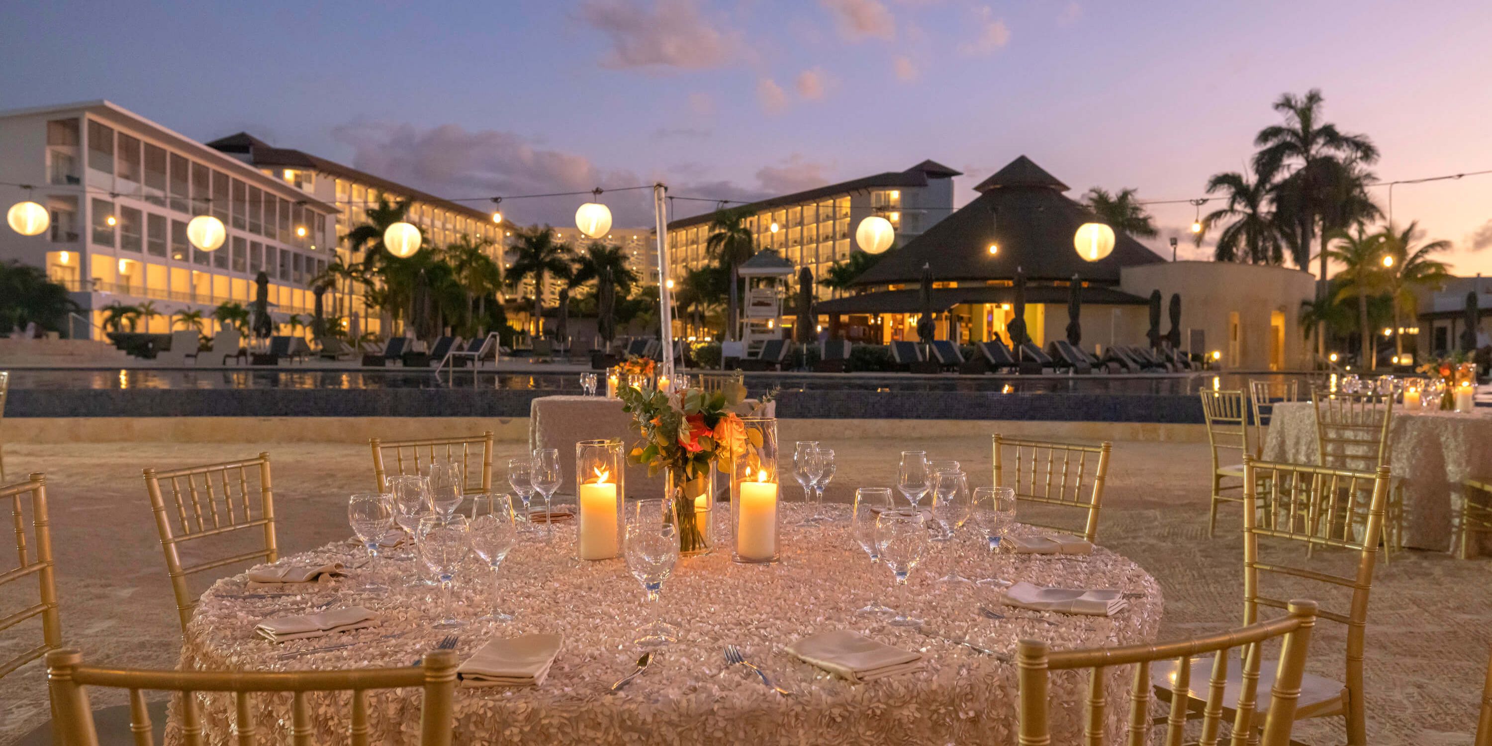 Round table with candles and flowers set for a destination wedding at Hideaway at Royalton Blue Waters poolside.