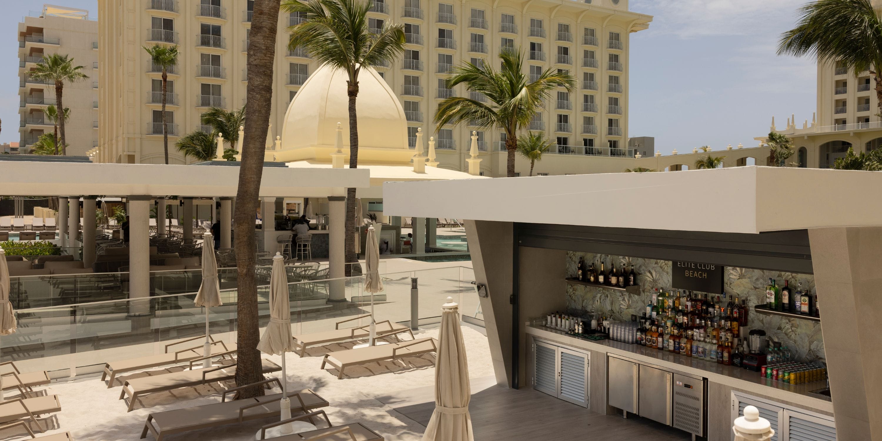 Hotel Riu Palace Aruba: outdoor bar, palm trees, lounge chairs—perfect for a destination wedding.