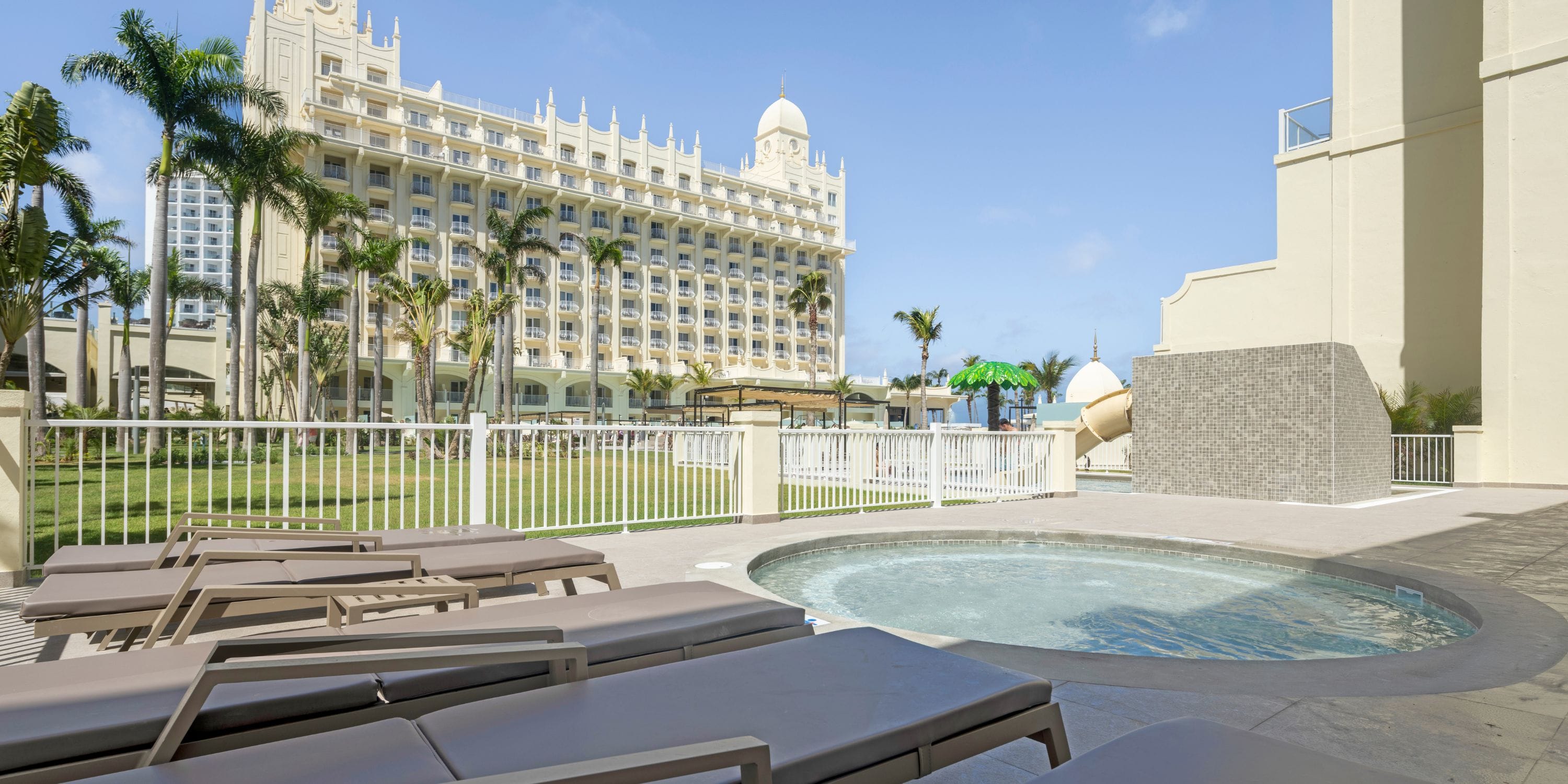 Lounge chairs by a pool at Hotel Riu Palace Aruba, an ideal spot for a destination wedding backdrop.