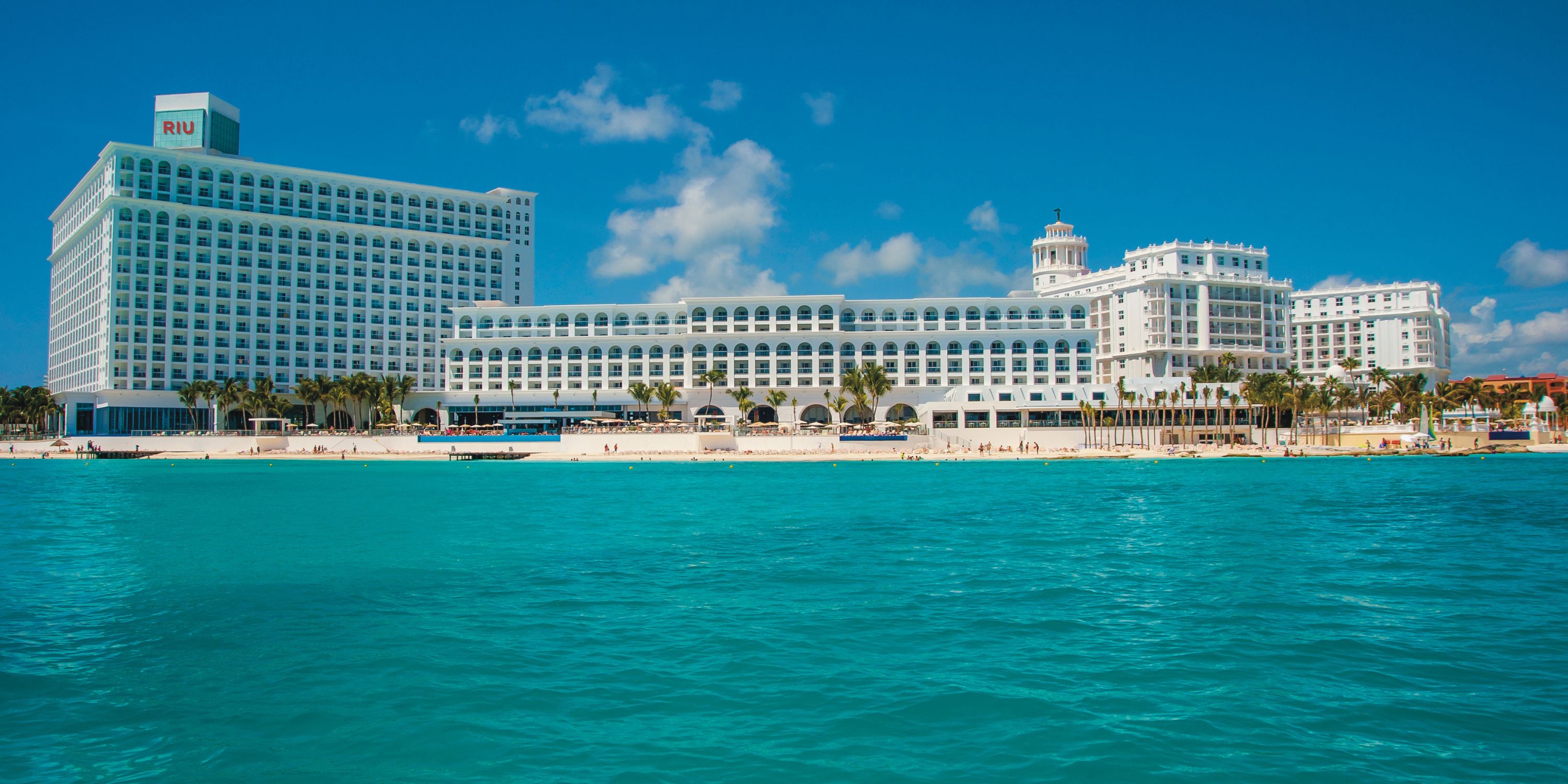 Hotel Riu Cancun: ideal for a destination wedding, this large white hotel sits by palm trees and blue water.