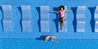 At a destination wedding, two guests relax at Hotel Riu Jalisco’s pool—one lounging, one swimming.