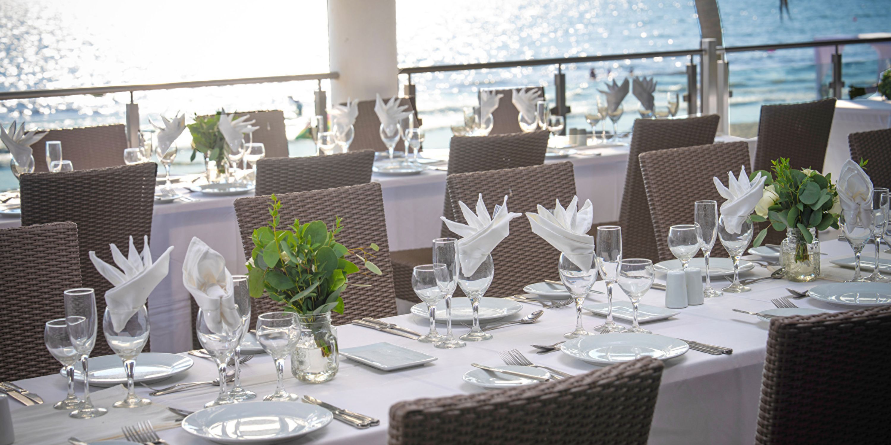 Elegant destination wedding dining at Hotel Riu Jalisco, white linens and florals by the waterfront.