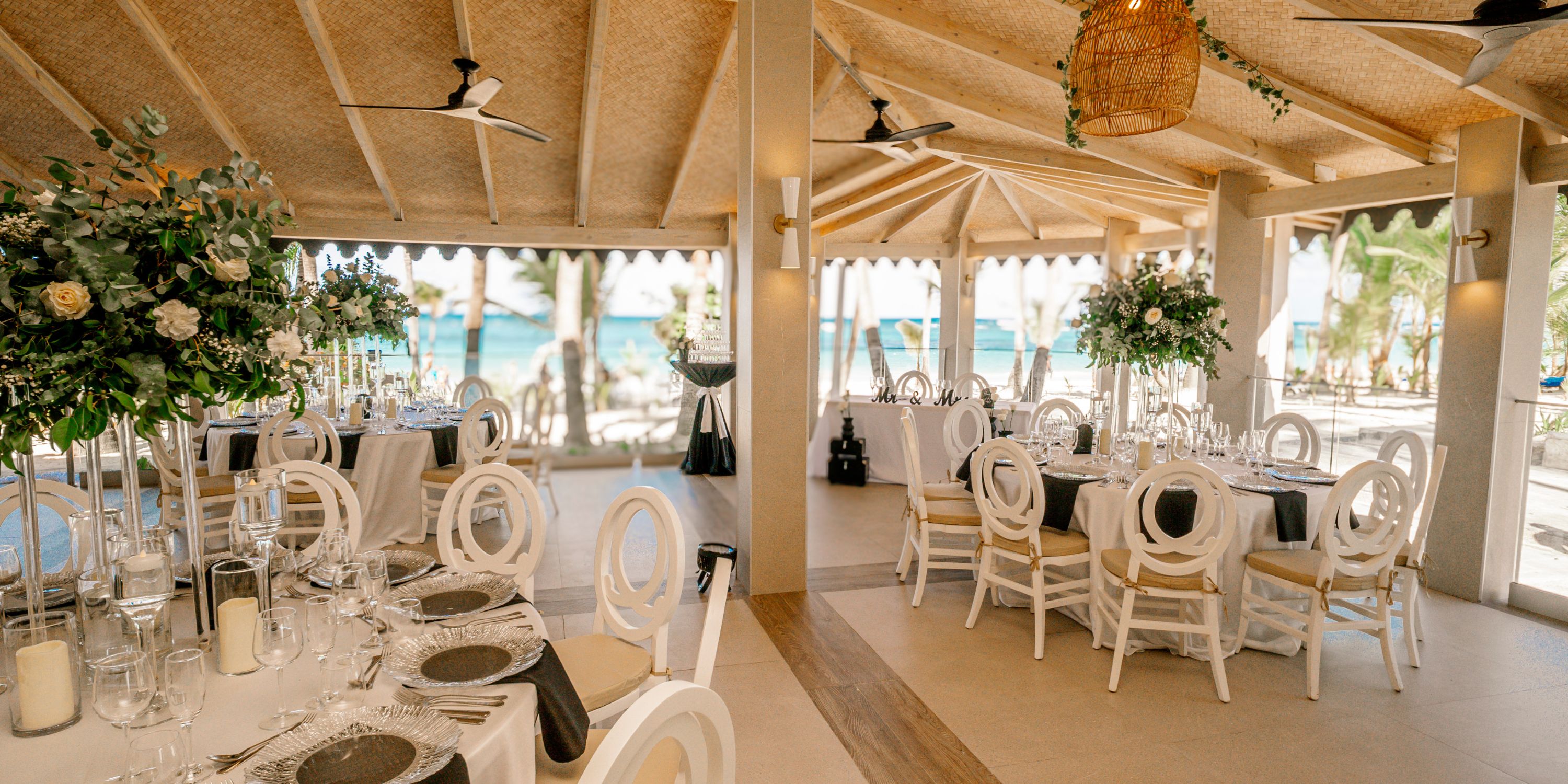 Chic destination wedding reception at Hotel Riu Bambu, featuring round tables and white chairs.