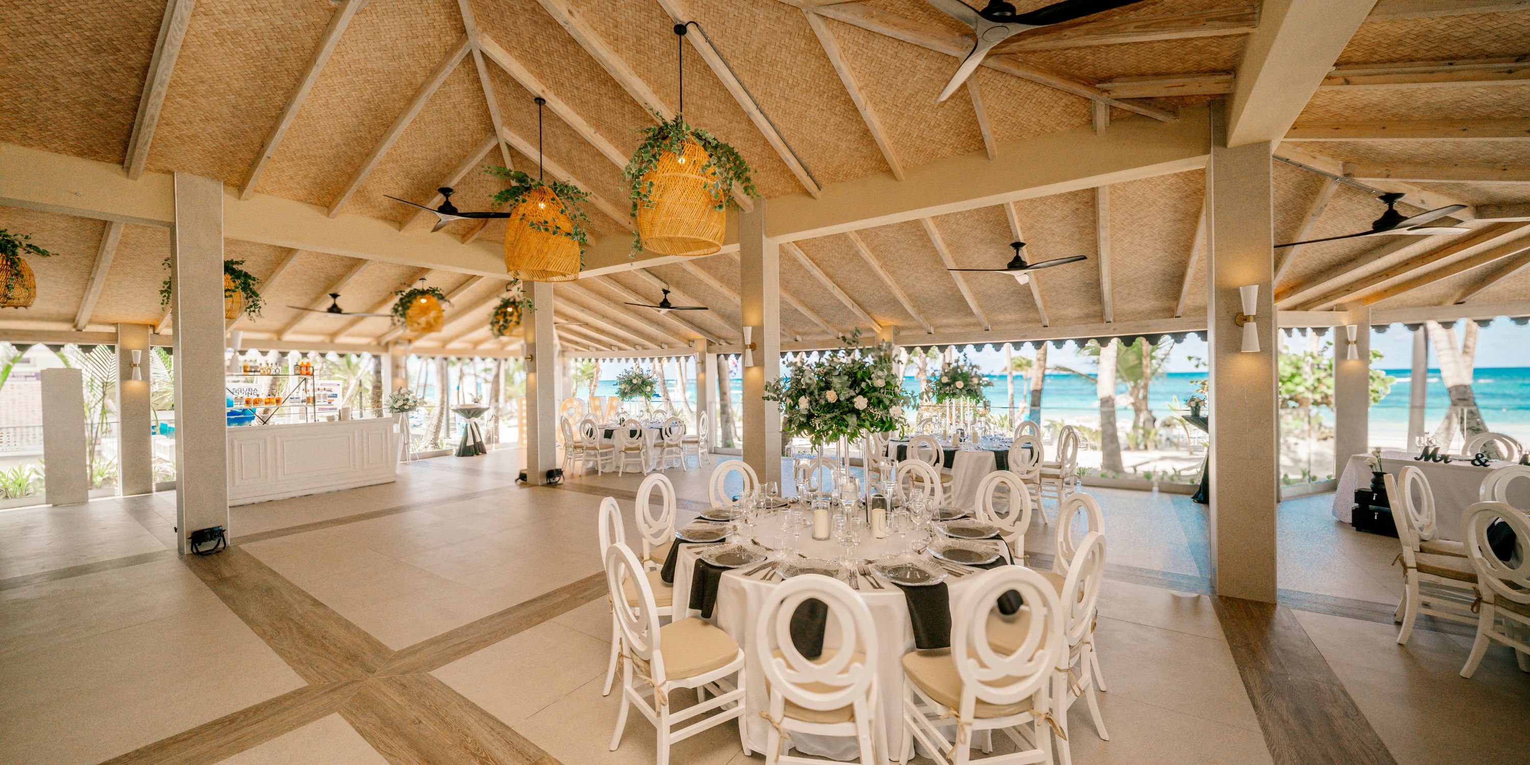 Hotel Riu Bambu: Elegant beachfront wedding venue with round tables and lush greenery for destination weddings.