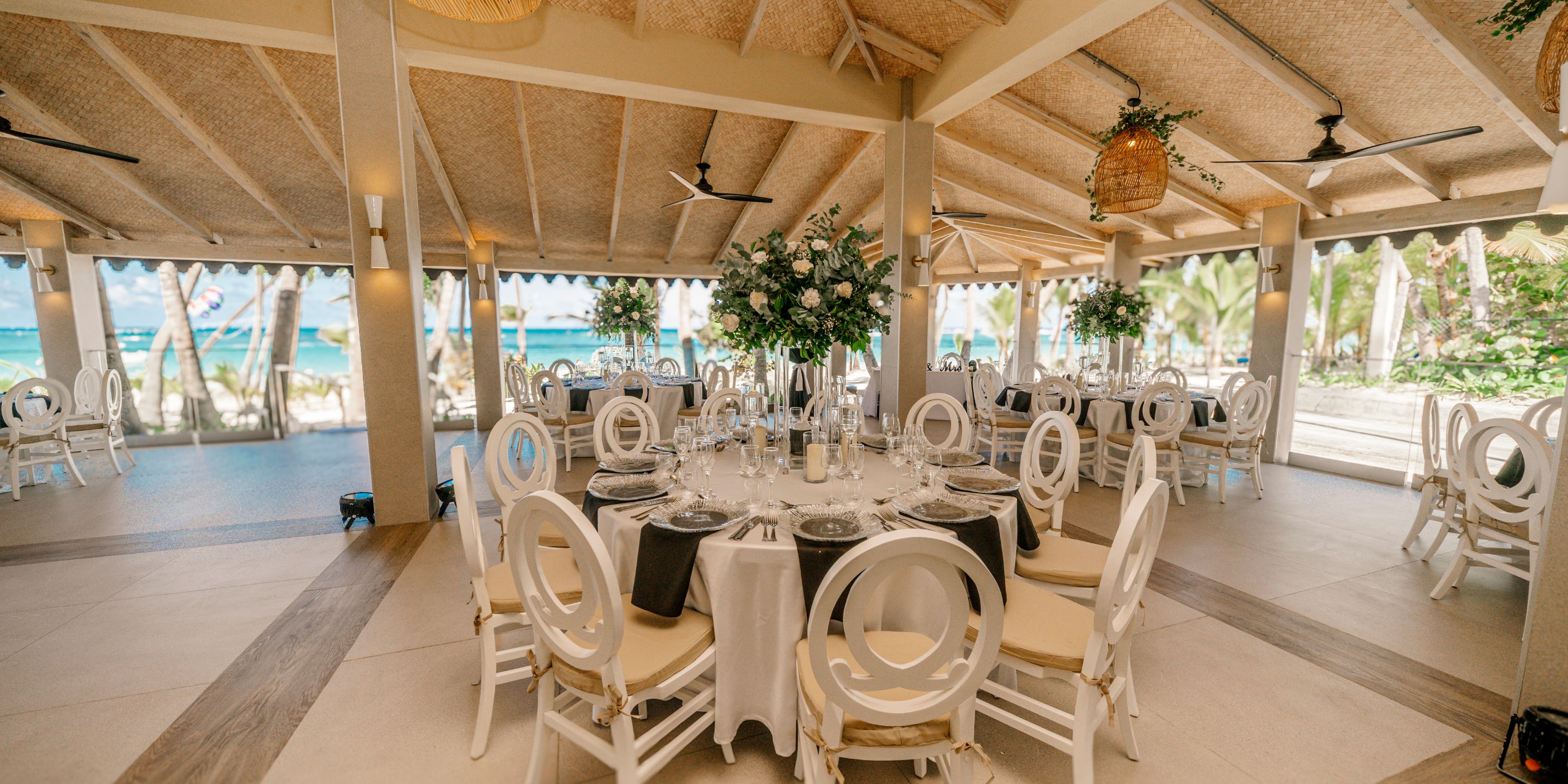 Hotel Riu Bambu features stunning beachside dining perfect for destination weddings, with round tables and white chairs.