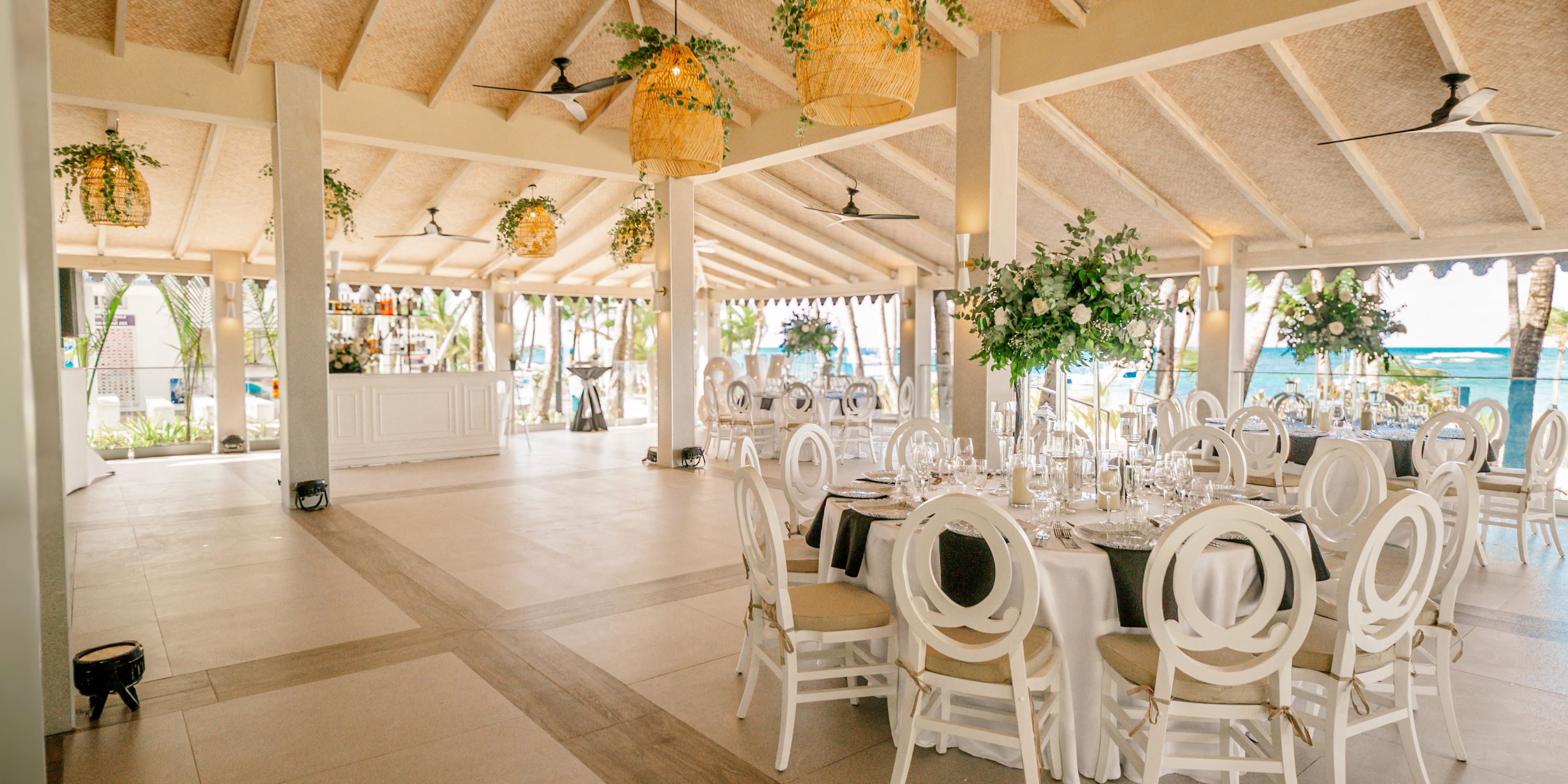 Hotel Riu Bambu features an elegant open-air wedding venue with round tables set near the beach.