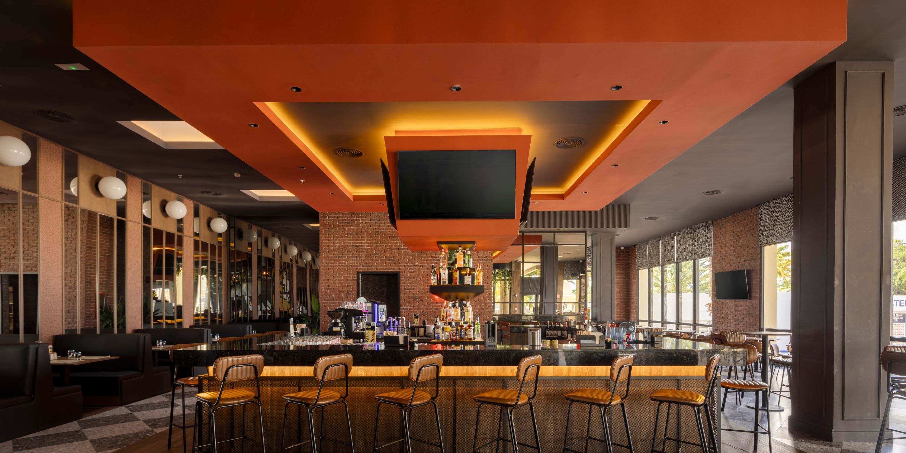 Hotel Riu Palace Aruba bar&mdash;ideal for a destination wedding, high stools, TVs, and orange lighting.