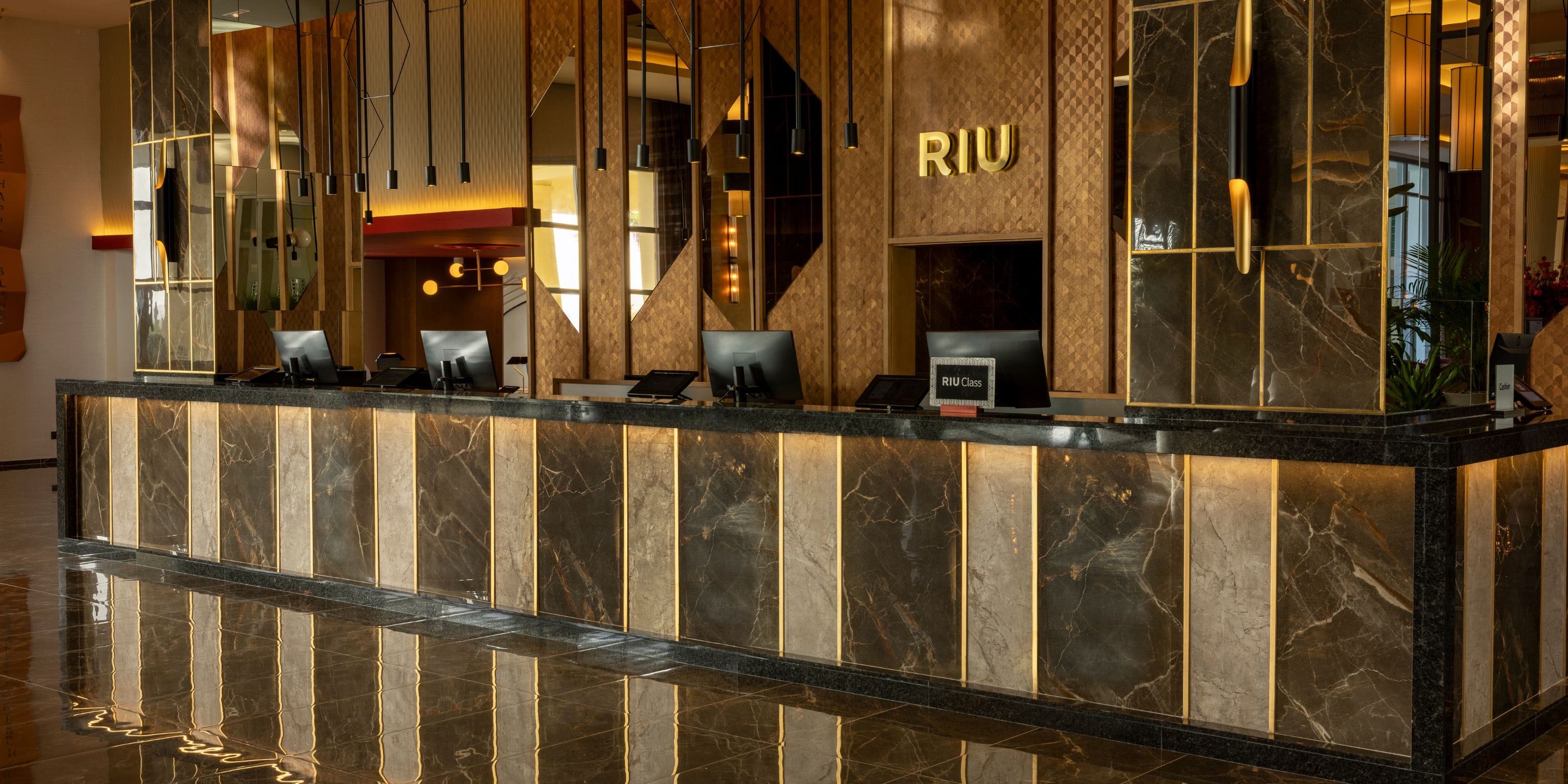 Hotel Riu Palace Aruba front desk, ideal for destination wedding guests; marble counters, RIU logo.
