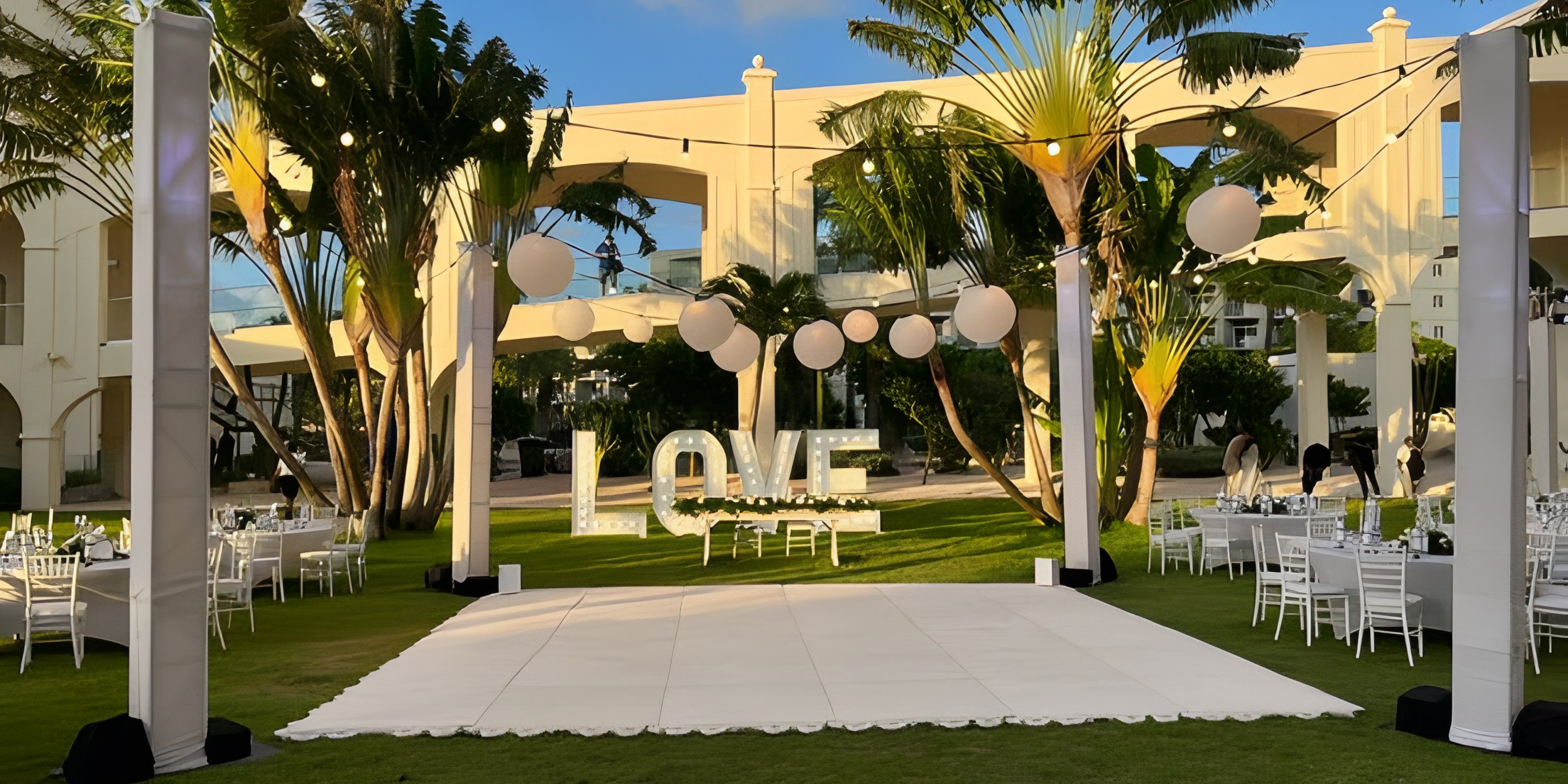 Destination wedding setup at Hotel Riu Palace Aruba with white dance floor, LOVE sign, and string lights.