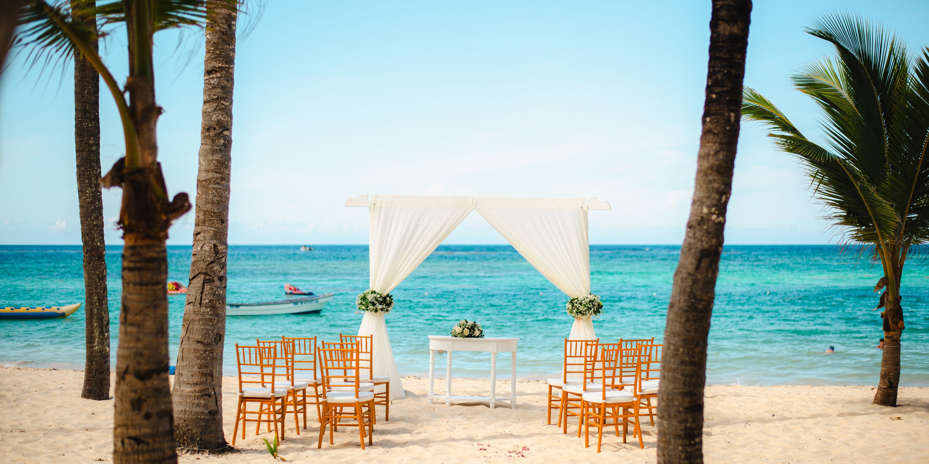 Destination wedding setup at Hotel Riu Palace Punta Cana with chairs and arch by the ocean.
