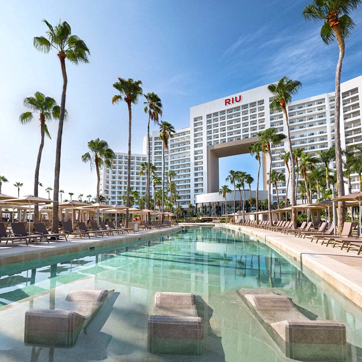 Outdoor pool with loungers and palm trees, ideal for a destination wedding at Riu Palace Peninsula.