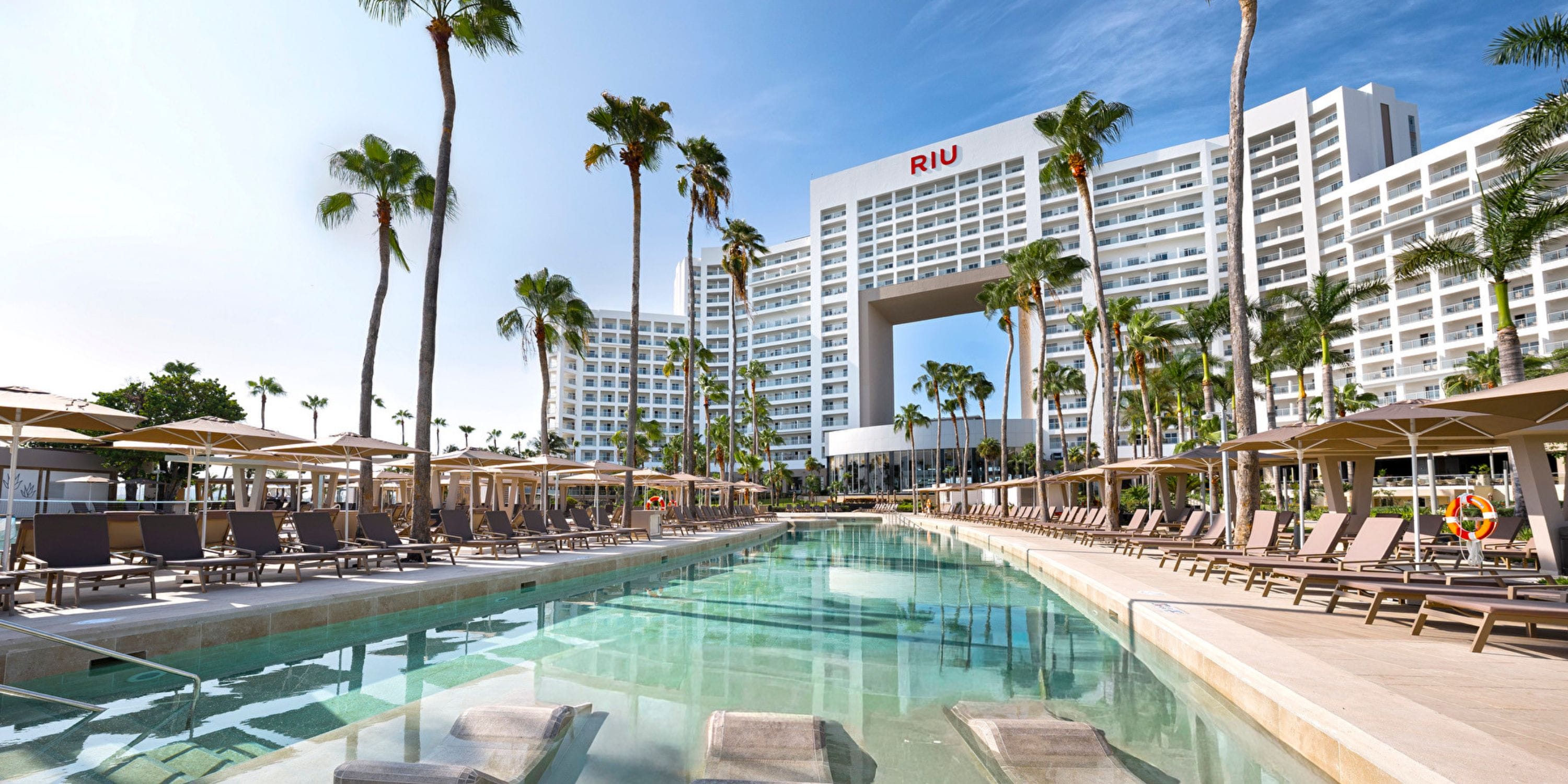 Hotel Riu Palace Peninsula: modern resort ideal for destination weddings, with pool and palm trees.